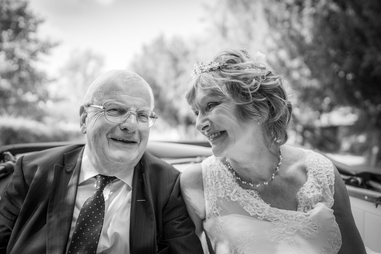 Black and white candid photo of a happy couple laughing together during a wedding celebration.
