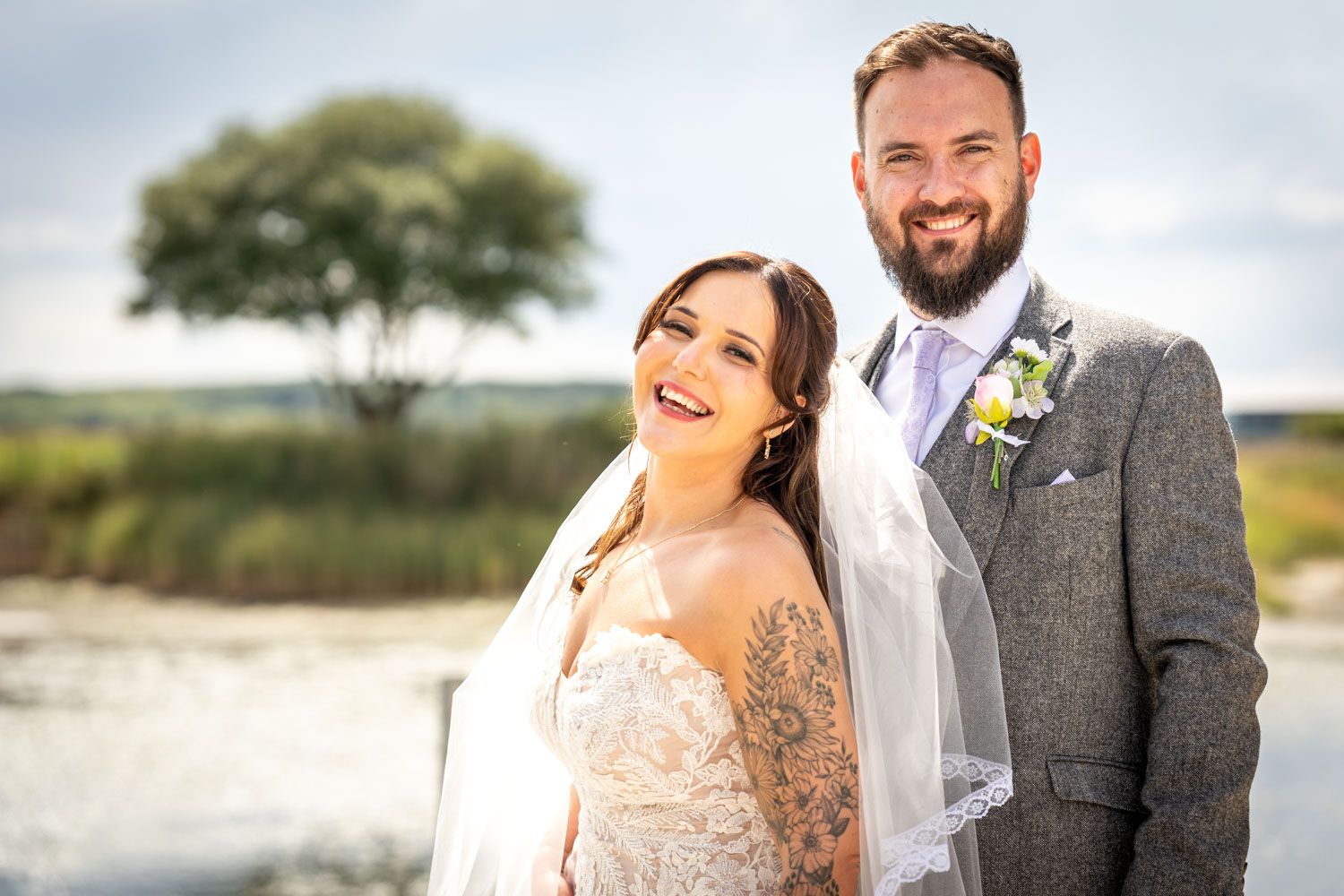 Smiling bride and groom portrait outdoors with scenic countryside background on their wedding day.