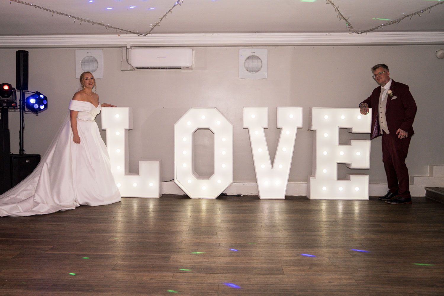 A large illuminated LOVE sign provides romantic decor at an indoor event venue.