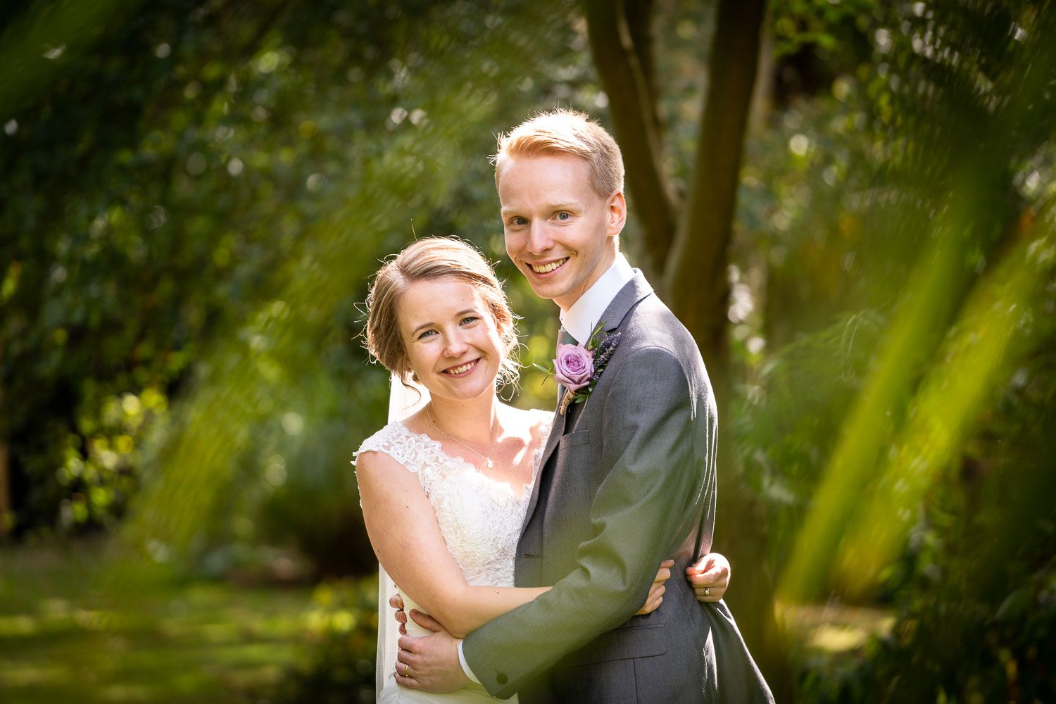 A summer wedding portrait taken in a lush garden setting with soft natural lighting.