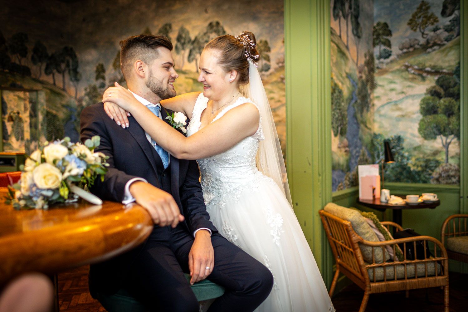 Intimate wedding portrait in vintage room with decorative wall murals and wooden furniture.