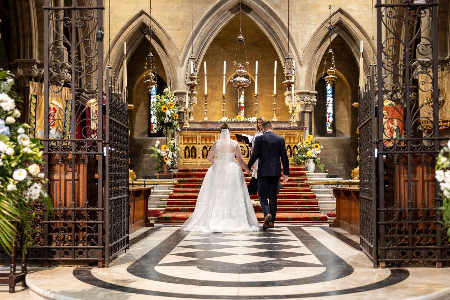 Gothic church interior with ornate altar and architectural details during wedding ceremony.