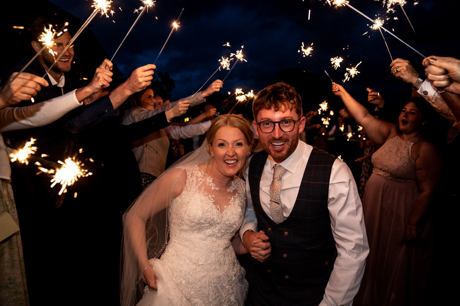 Wedding celebration at night with sparklers creating a magical light display against the dark sky.