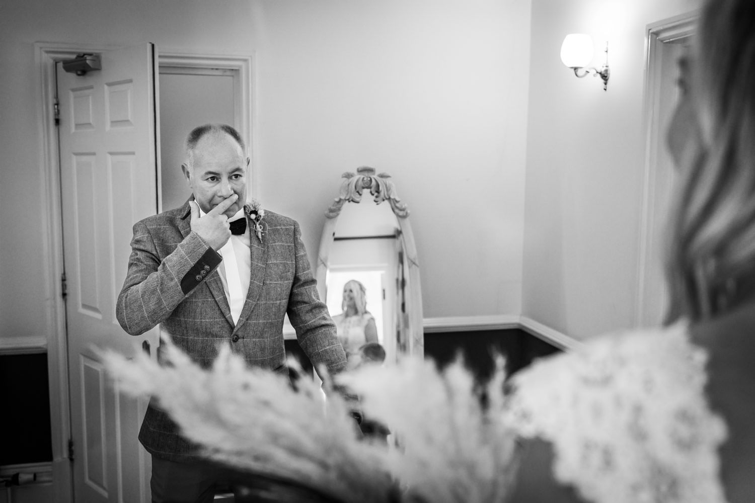 An emotional moment captured in black and white as someone adjusts their bow tie before a special event.