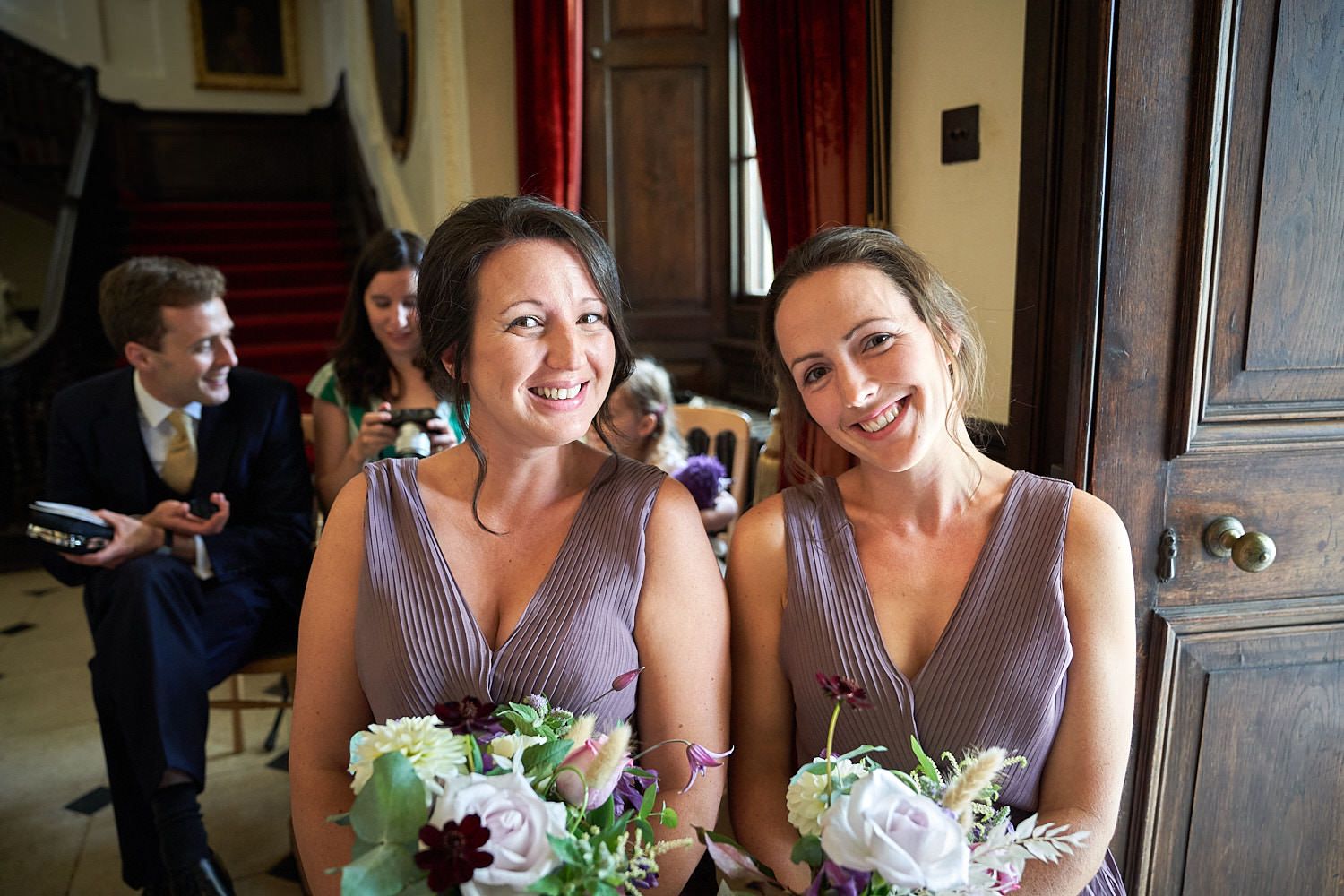 Bridesmaids in lavender dresses hold flower bouquets while sharing a joyful moment during the wedding.