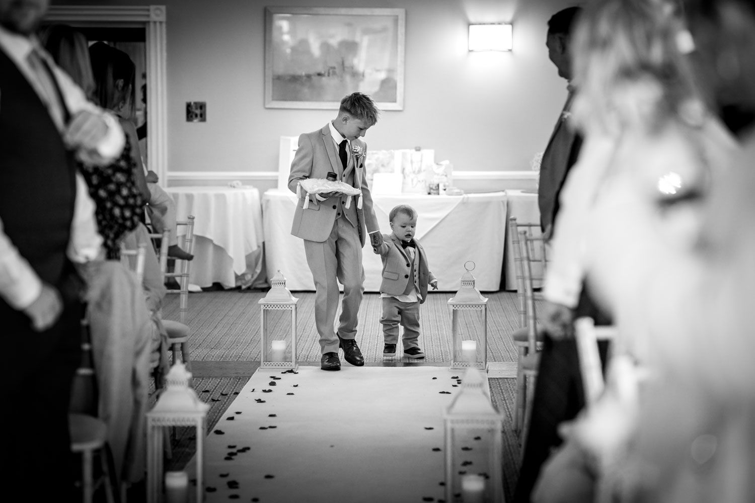 A heartwarming black and white wedding moment captured on an aisle decorated with scattered rose petals.