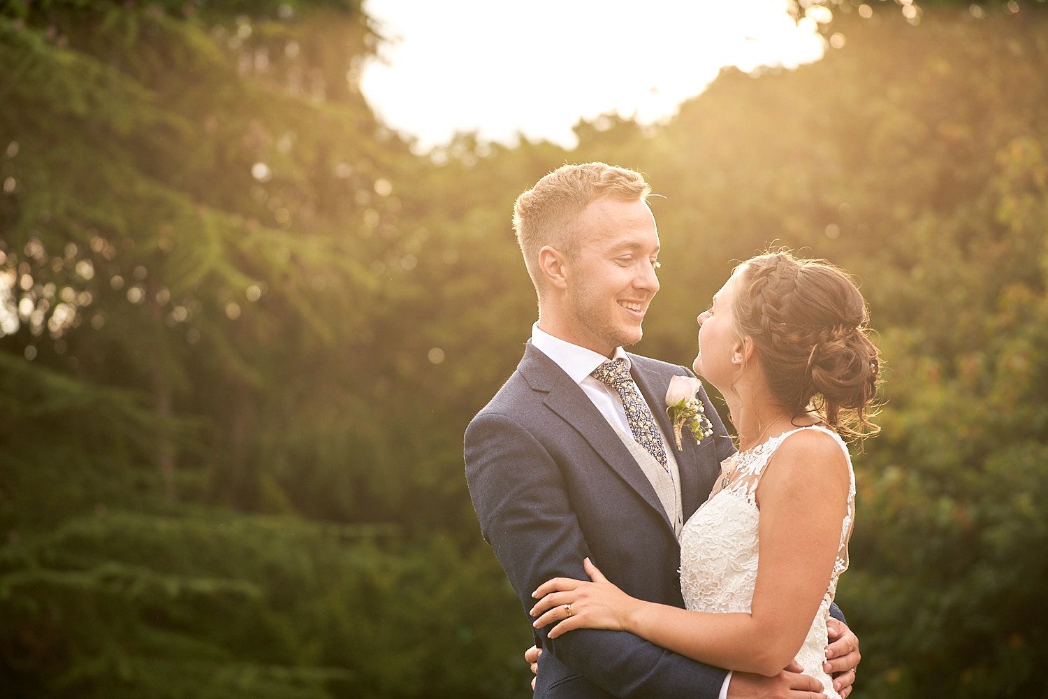 Newlyweds share a joyful embrace while bathed in golden sunset light during their outdoor wedding photoshoot.