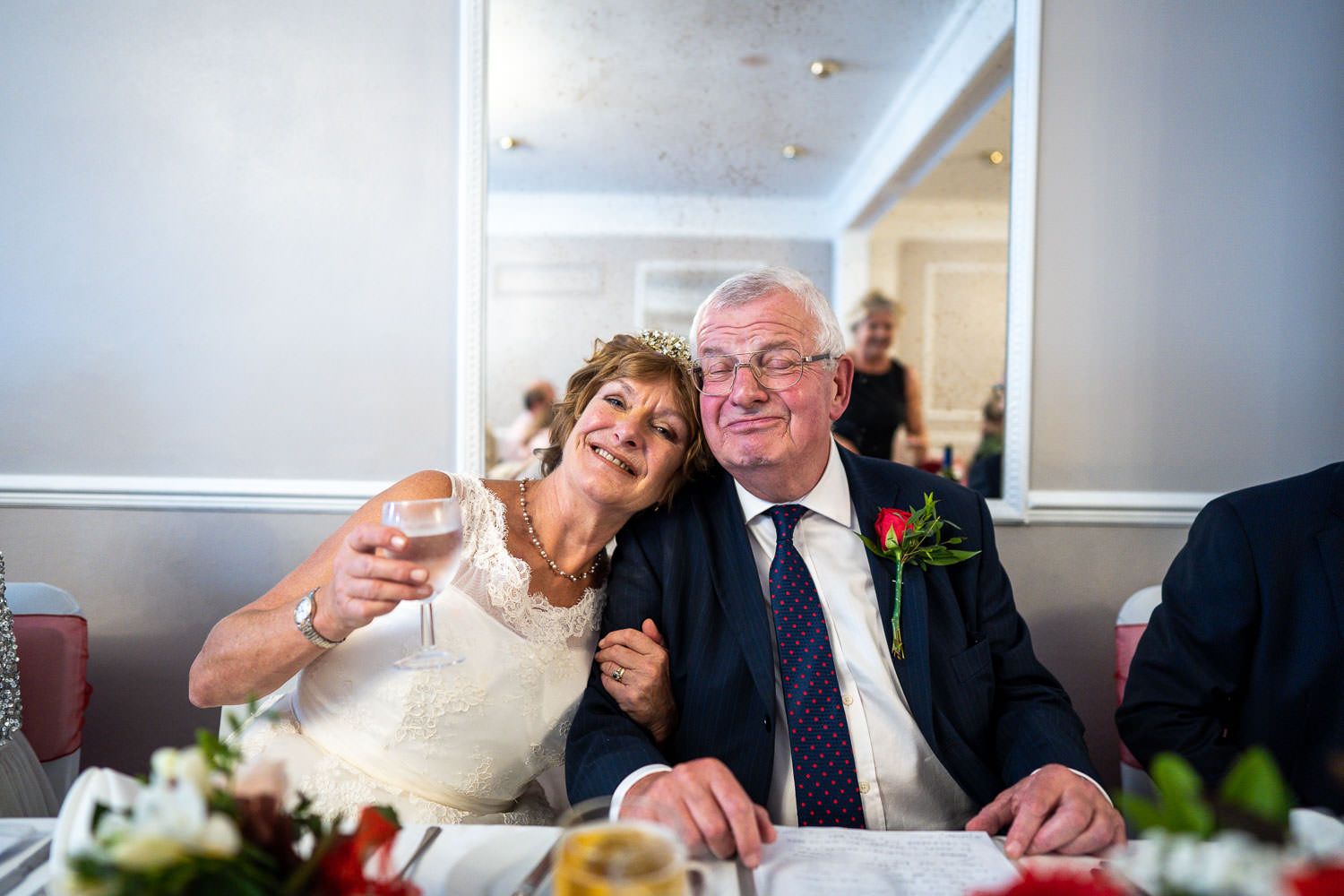 A happy couple enjoys a celebratory moment together at an elegant wedding reception table.