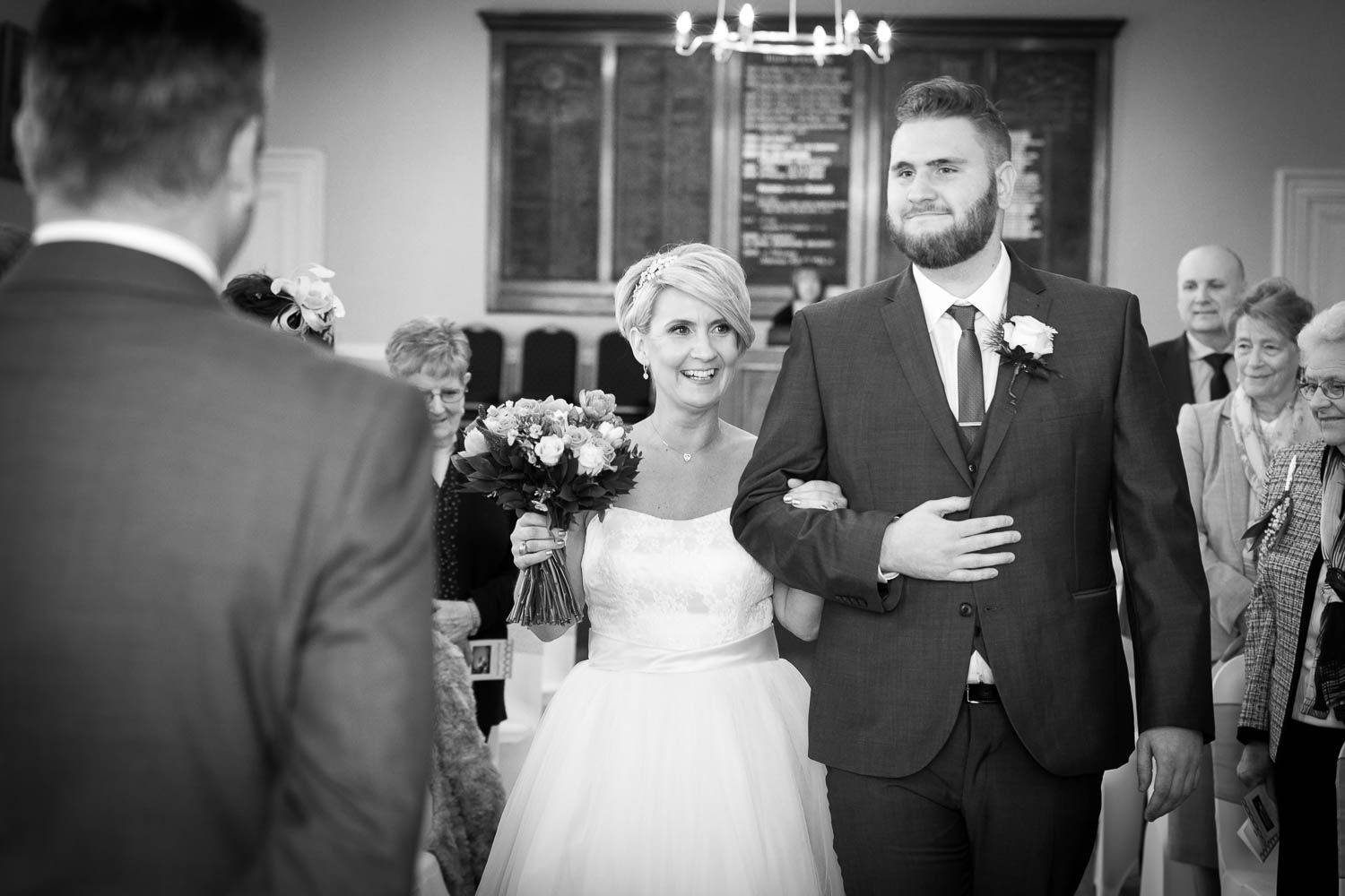 A black and white photograph captures a joyful couple during their wedding ceremony in a church setting.