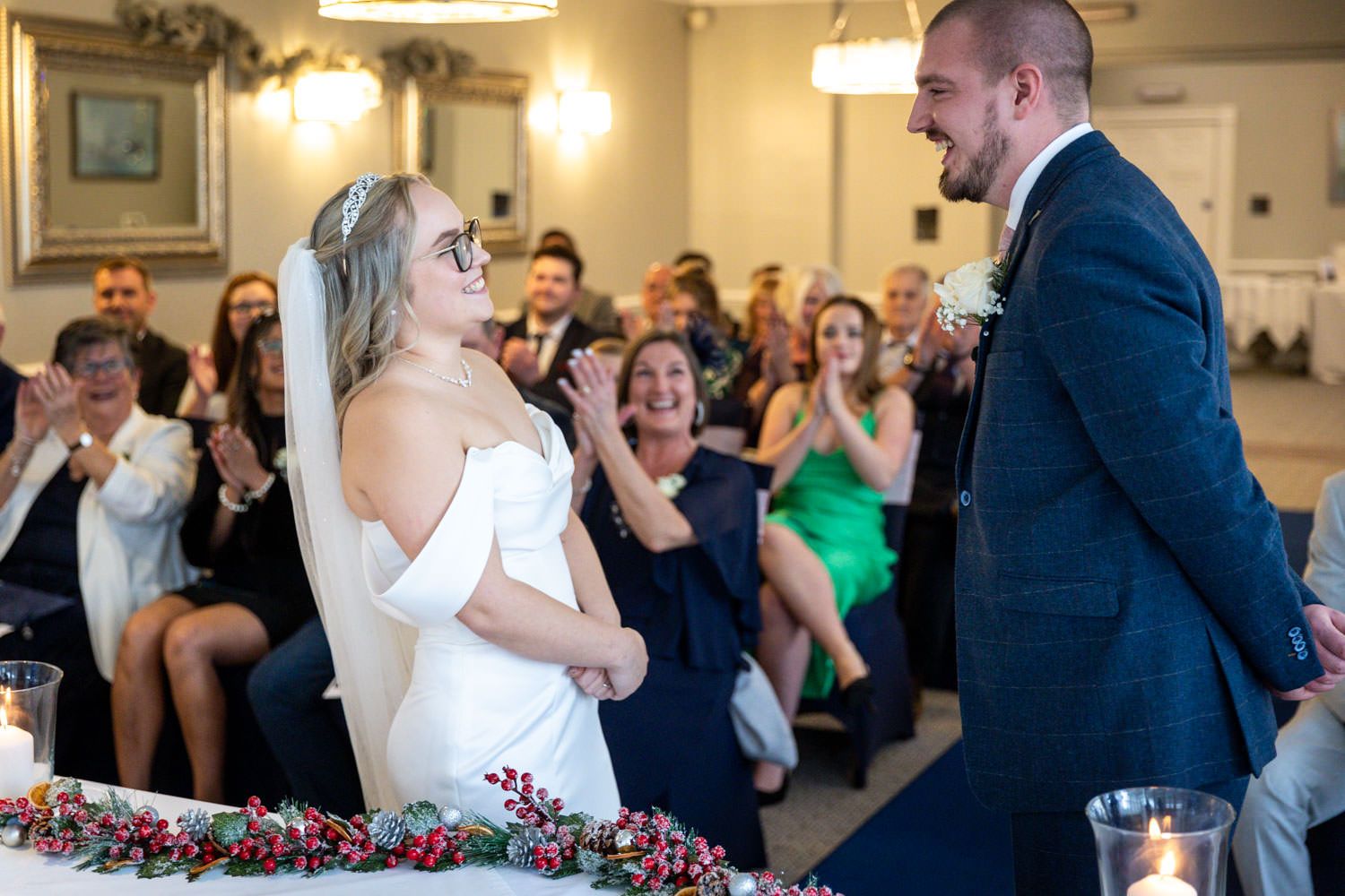 A wedding ceremony with guests looking on as couple shares a joyful moment in an elegant indoor venue.