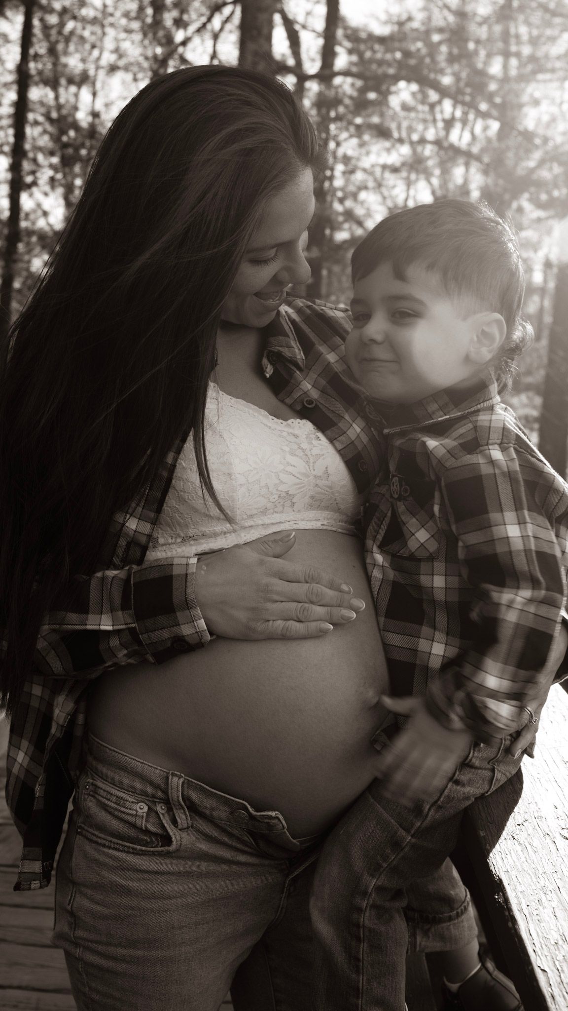 A series of black and white photos showing a pregnant woman's belly with a child embracing it in a tender moment.