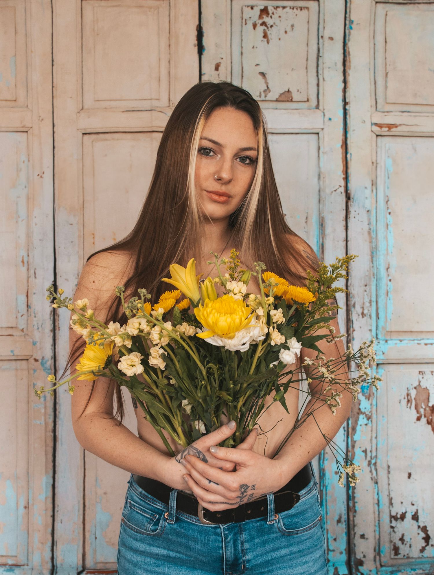 Four identical floral arrangements with yellow and white flowers displayed against a rustic blue wooden wall.