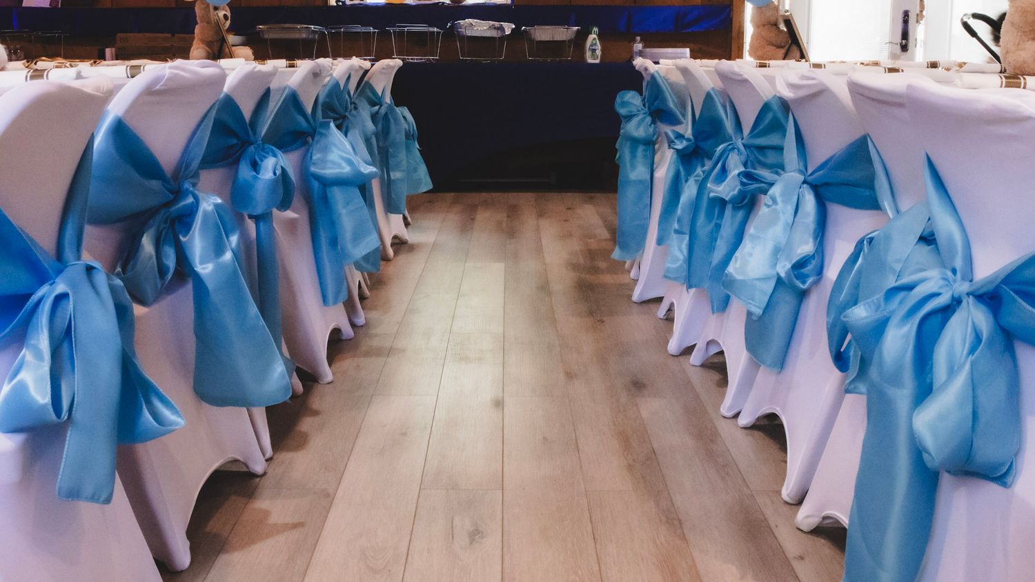 Row of chairs decorated with blue satin bows and white covers.