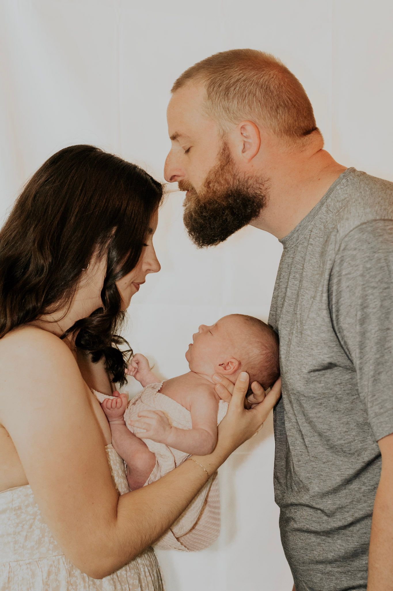 A series of tender moments between parents and their newborn baby against a light gray background.