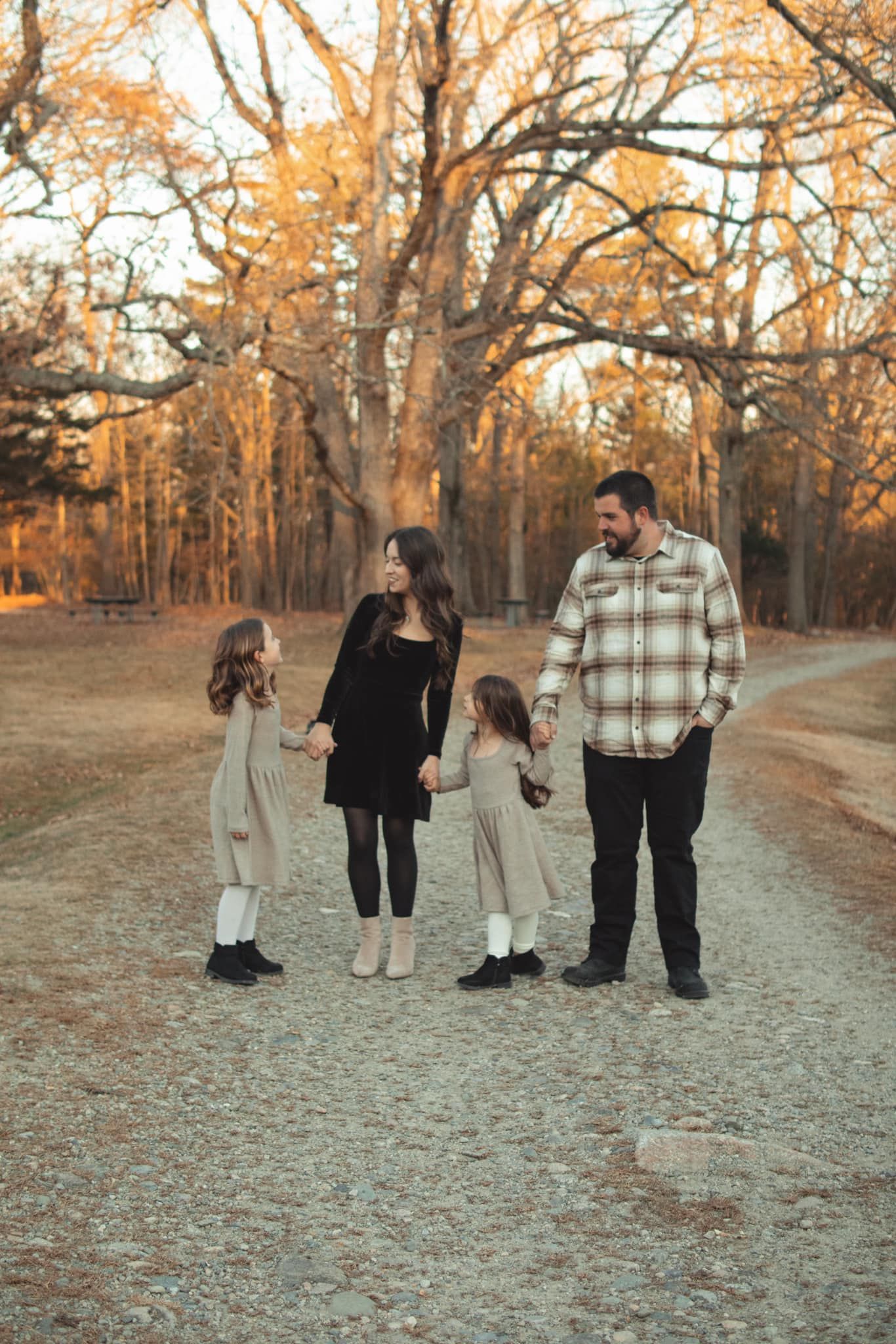 Family walking together on a gravel path during golden hour in autumn woods.