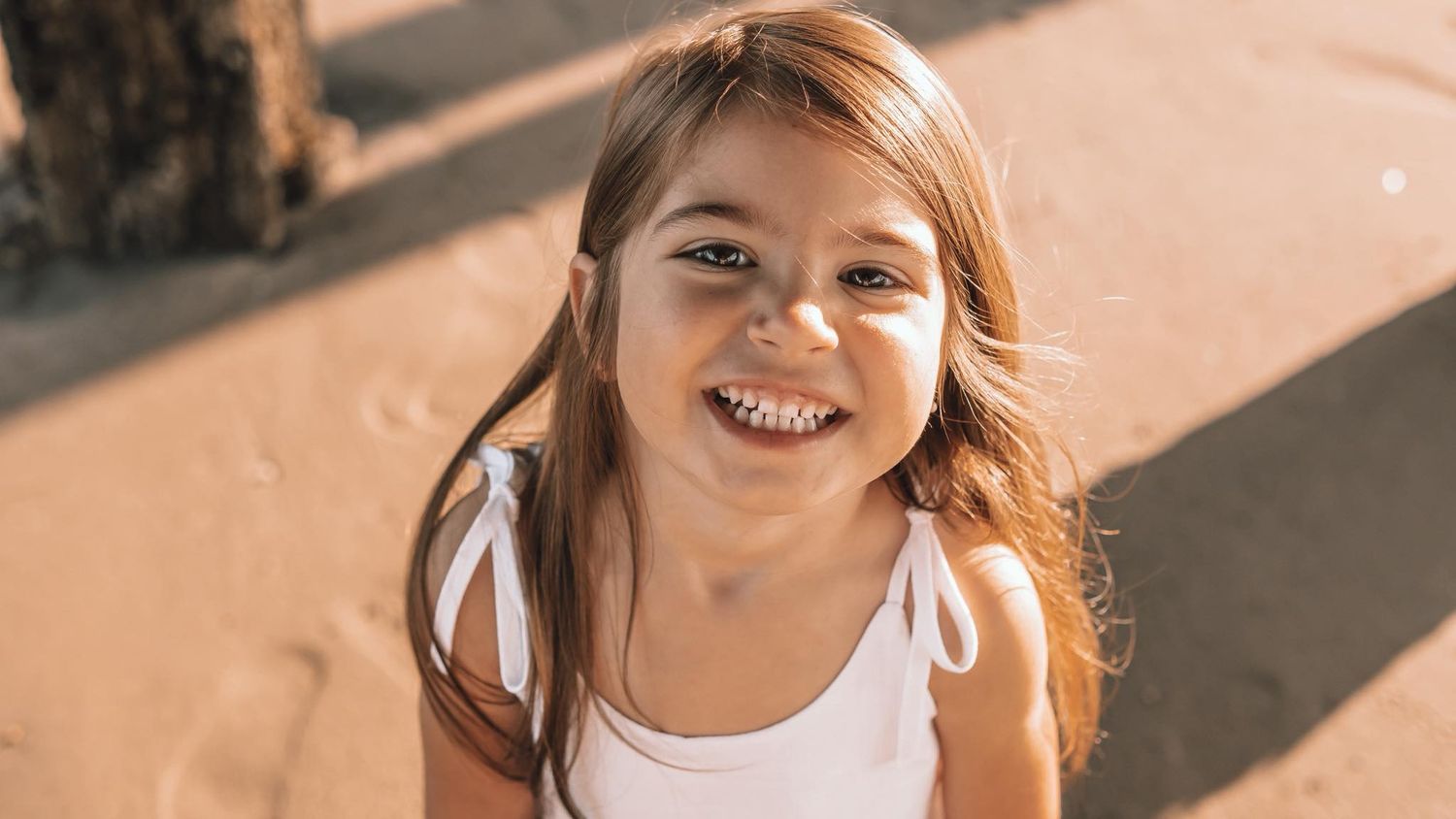 Woman with red hair smiling joyfully in warm sunlight.