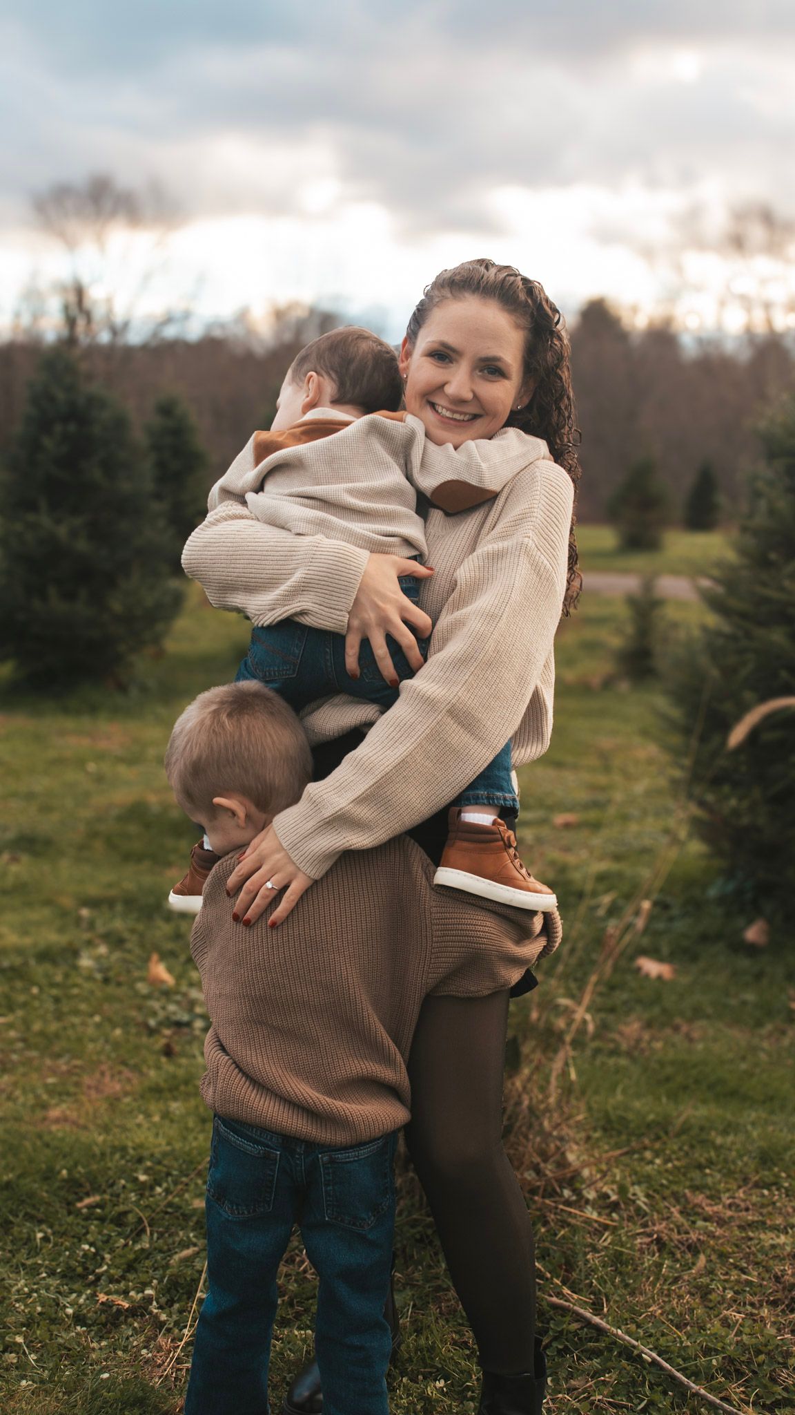 Sweet candid moments of hugs and laughter between family members in a rustic outdoor setting at sunset.