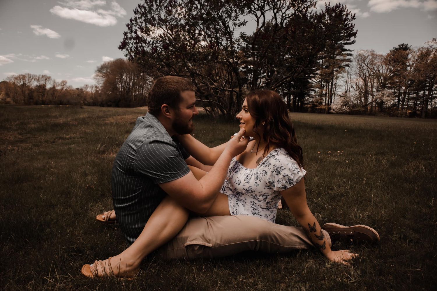Couple sharing intimate moment in rustic field during golden hour.