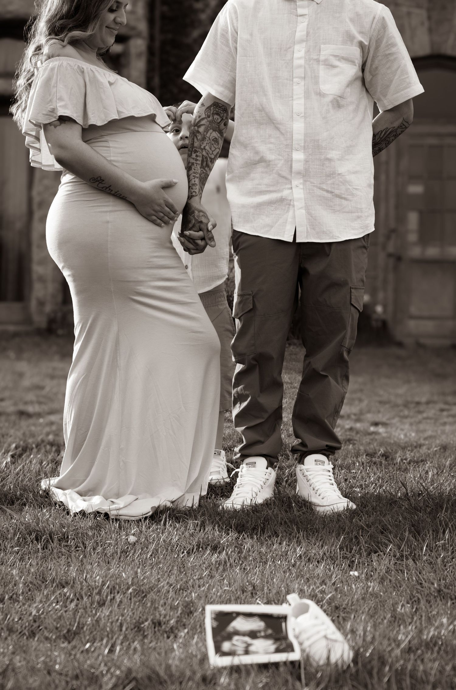 Sepia-toned maternity session showing details of family interactions outdoors.