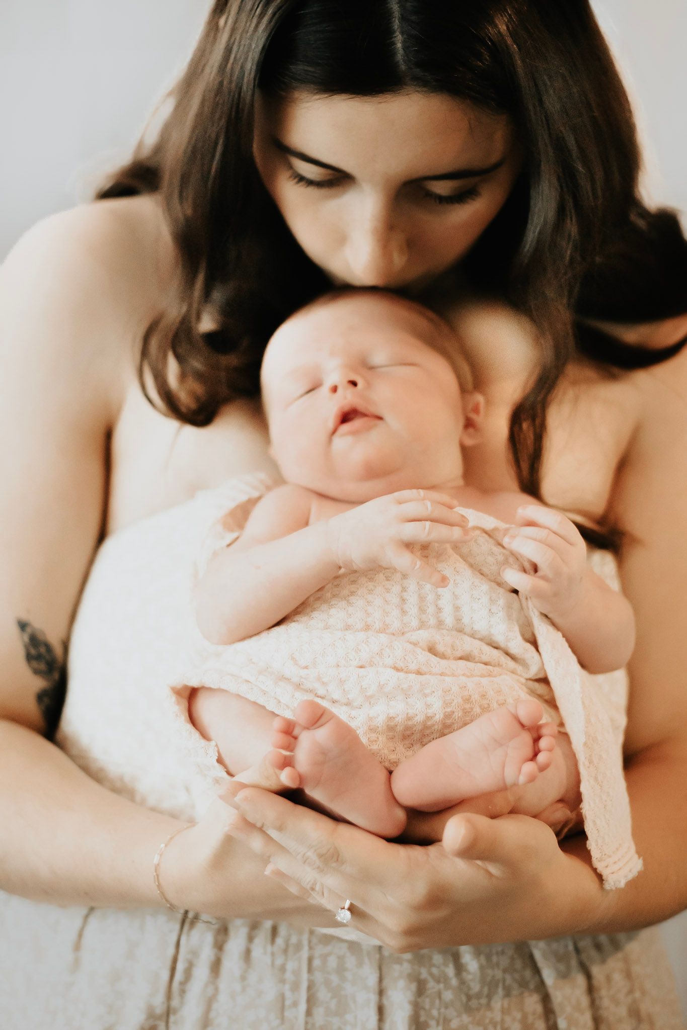 Close-up maternity photos in soft lighting showing gentle hands cradling belly.