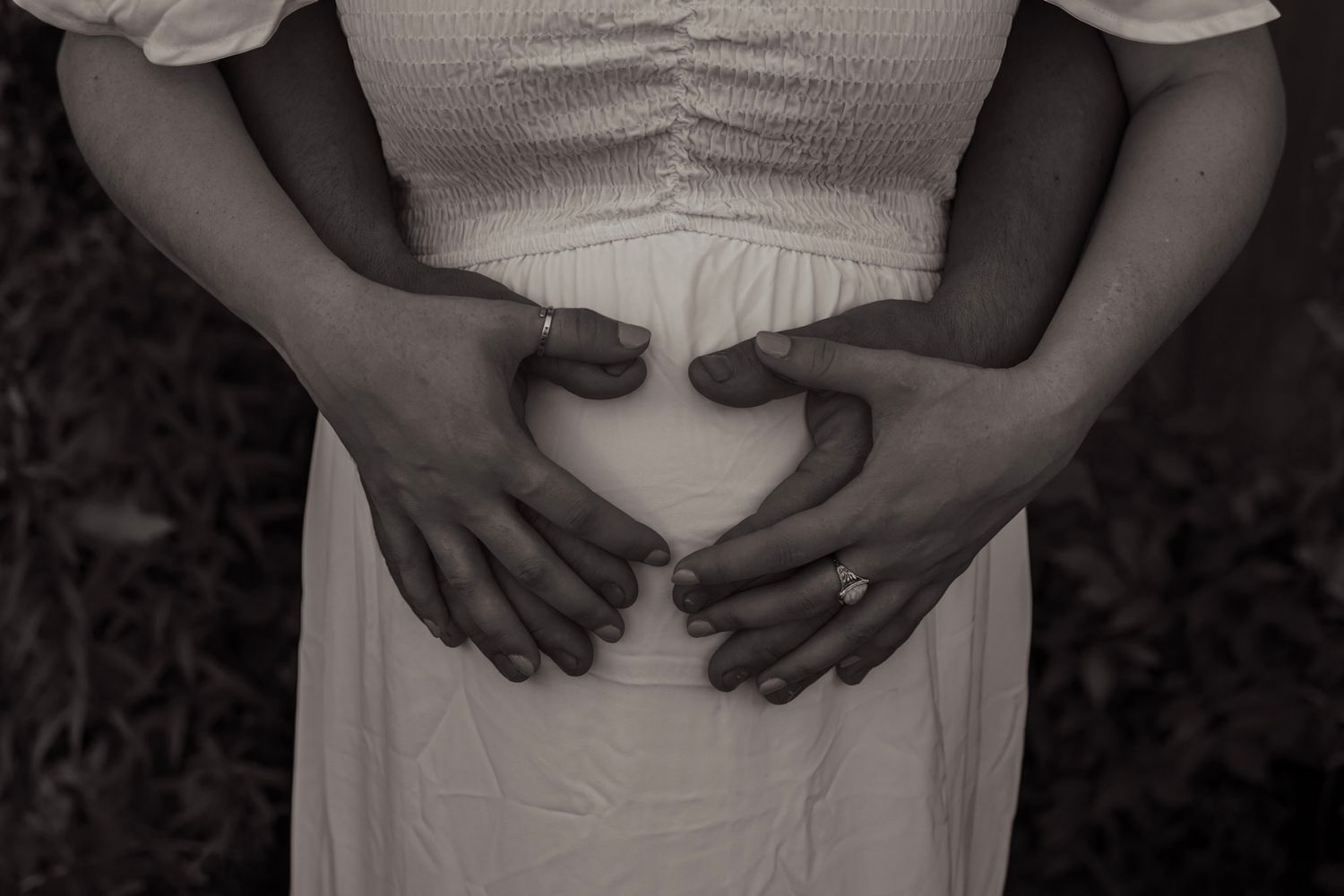 A series of black and white photos showing hands resting on a pregnant belly in different poses.