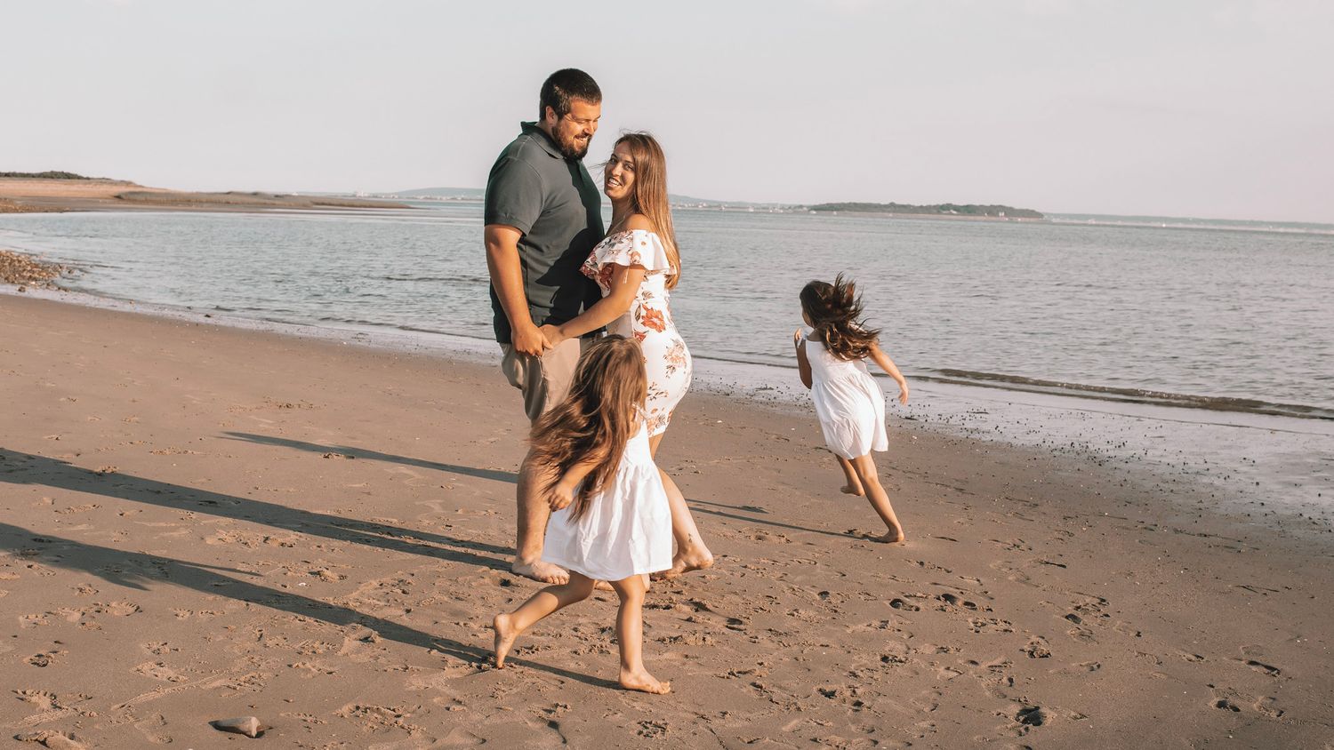 A couple walks along a scenic beach at sunset holding hands and enjoying the peaceful coastline.