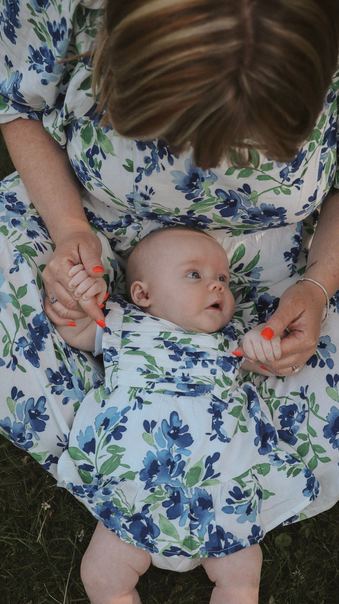A series of connected photos showing hands holding a small baby against a blue and white floral dress background.