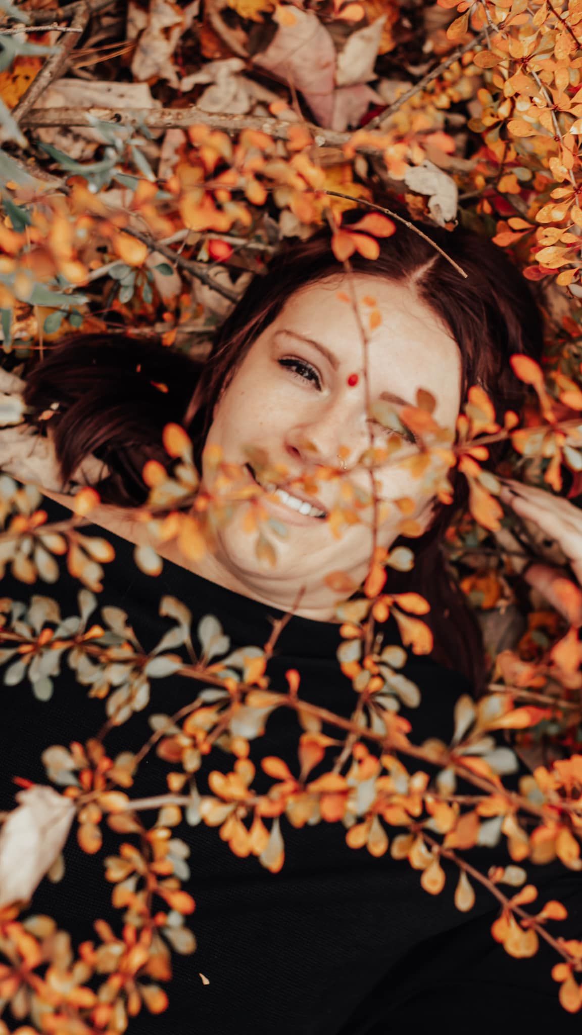 Autumn portrait surrounded by orange leaves and natural lighting.