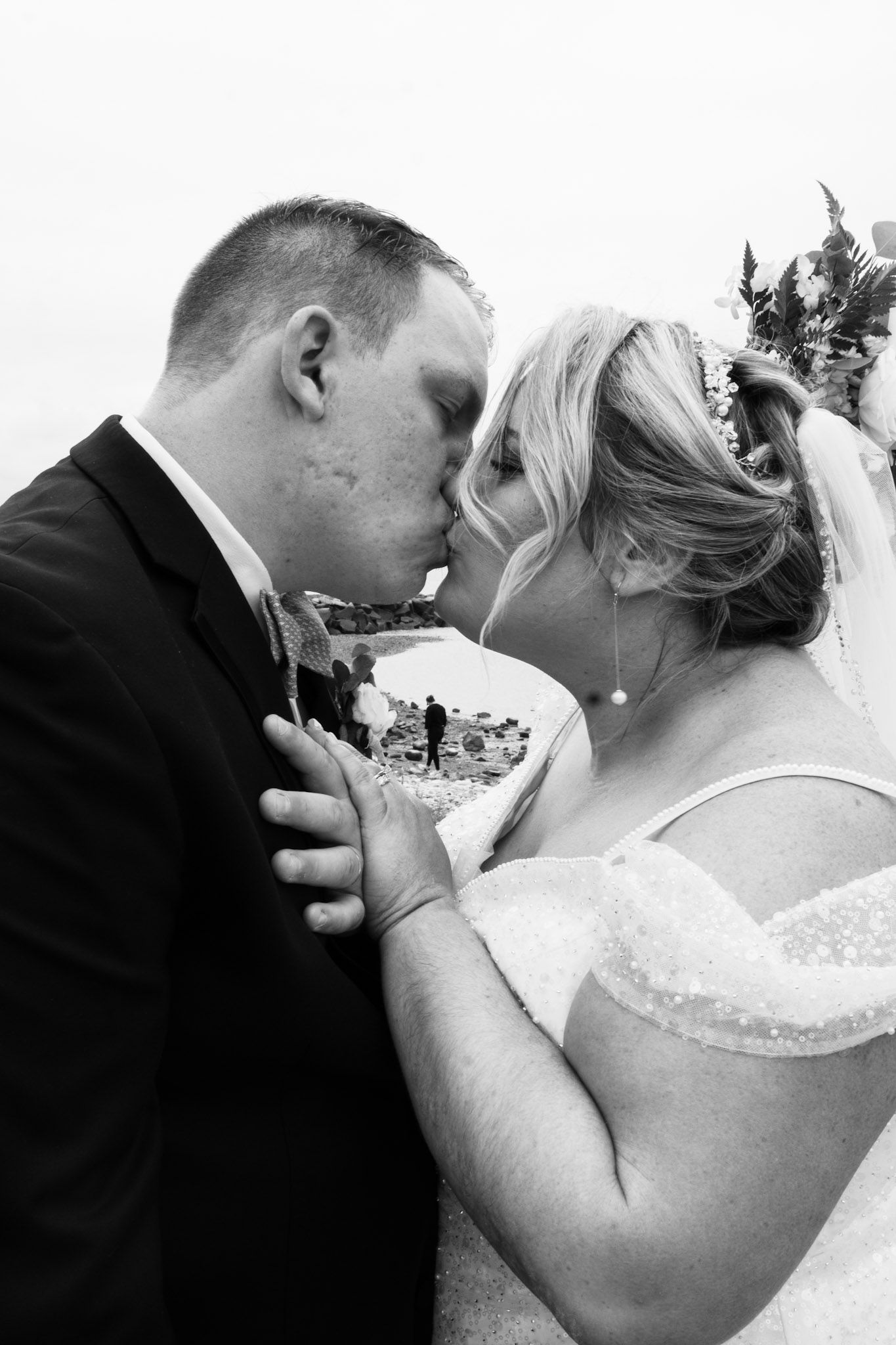 A series of black and white wedding photographs showing tender kisses between a couple in formal attire.