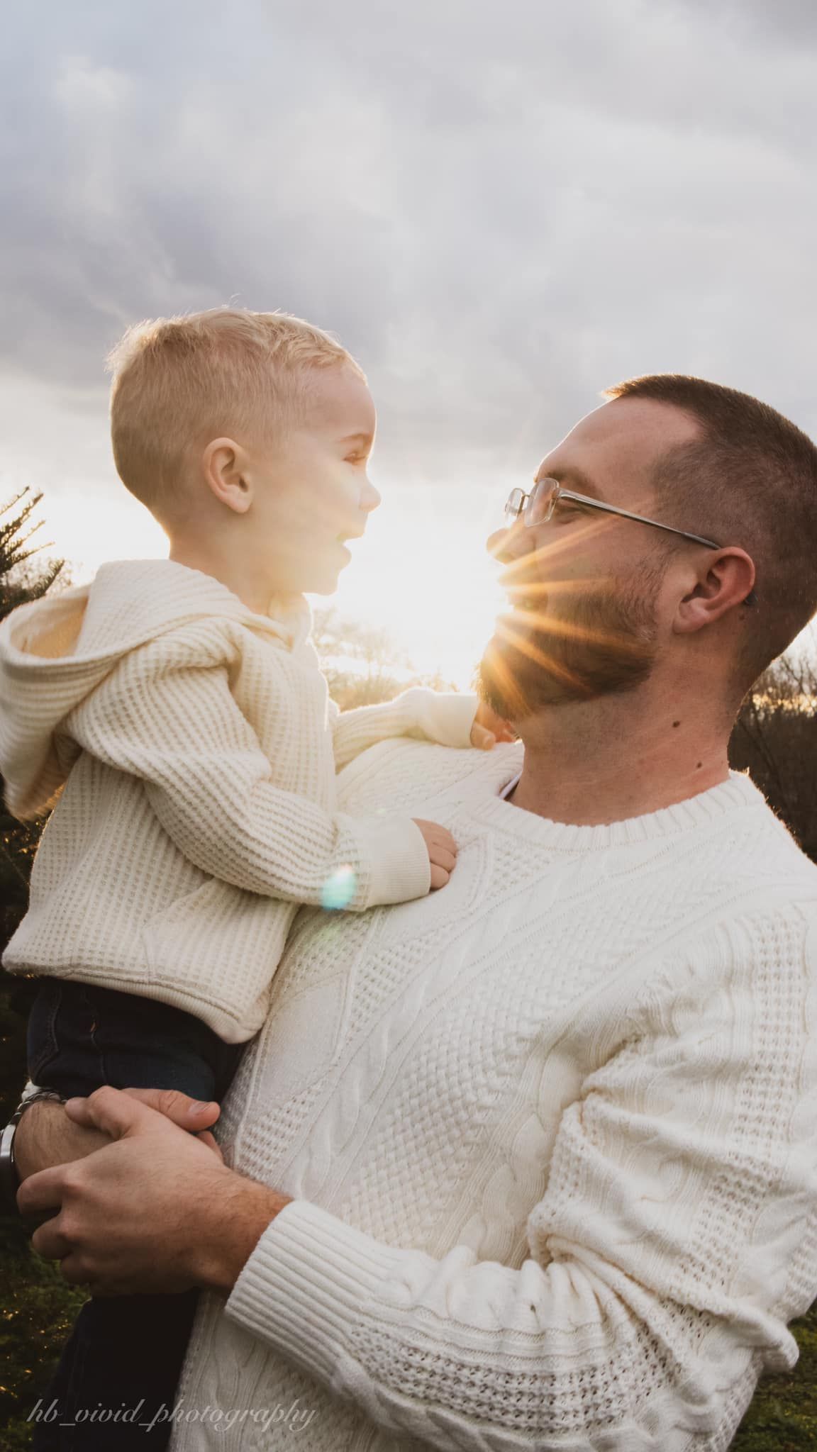 Sweet family moment captured against sunset with white knit sweaters.