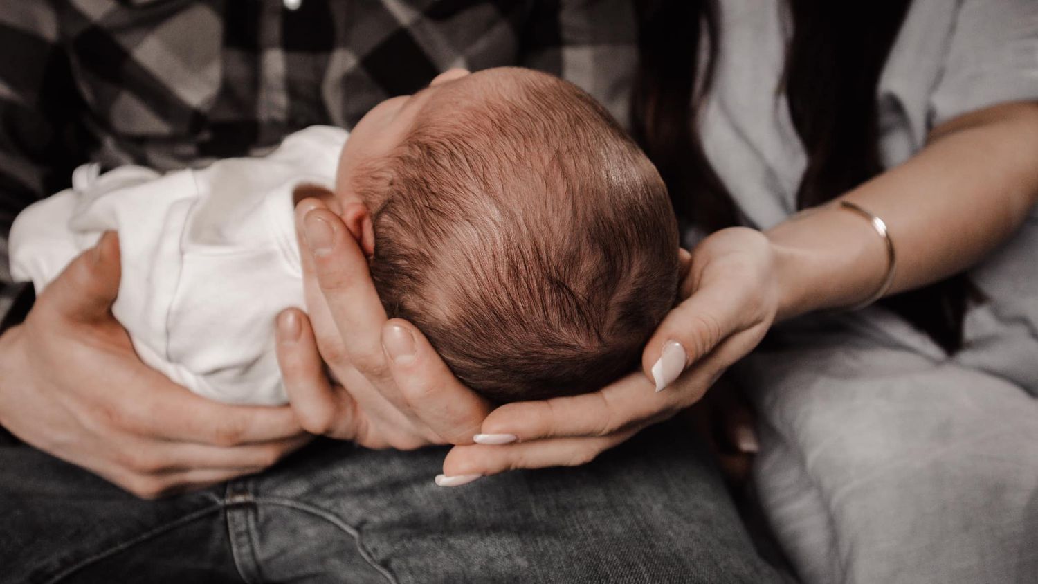Close-up shots of gentle hands holding a newborn baby.