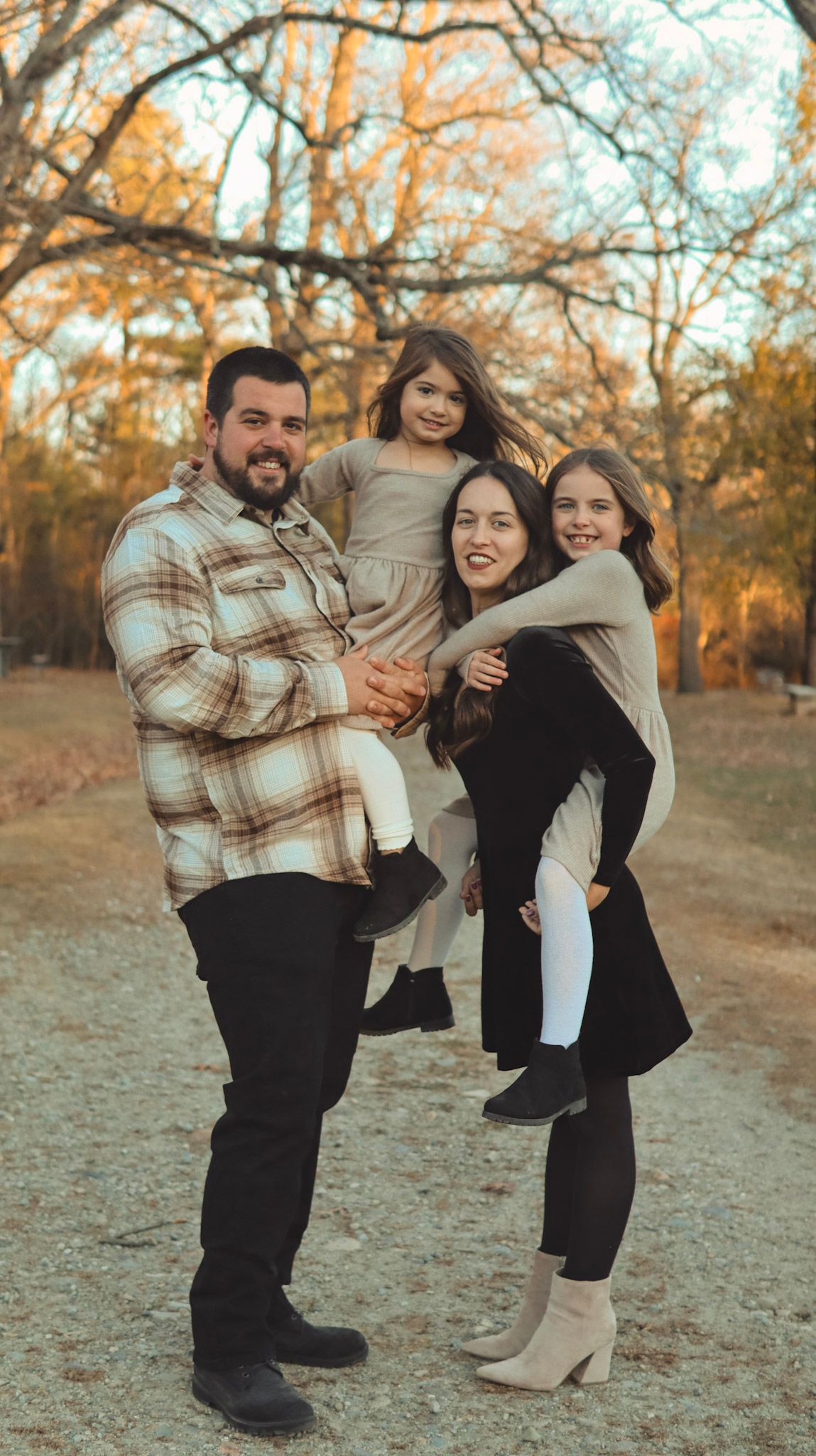 A group poses playfully in autumn scenery wearing plaid and neutral colors while enjoying a candid outdoor moment.
