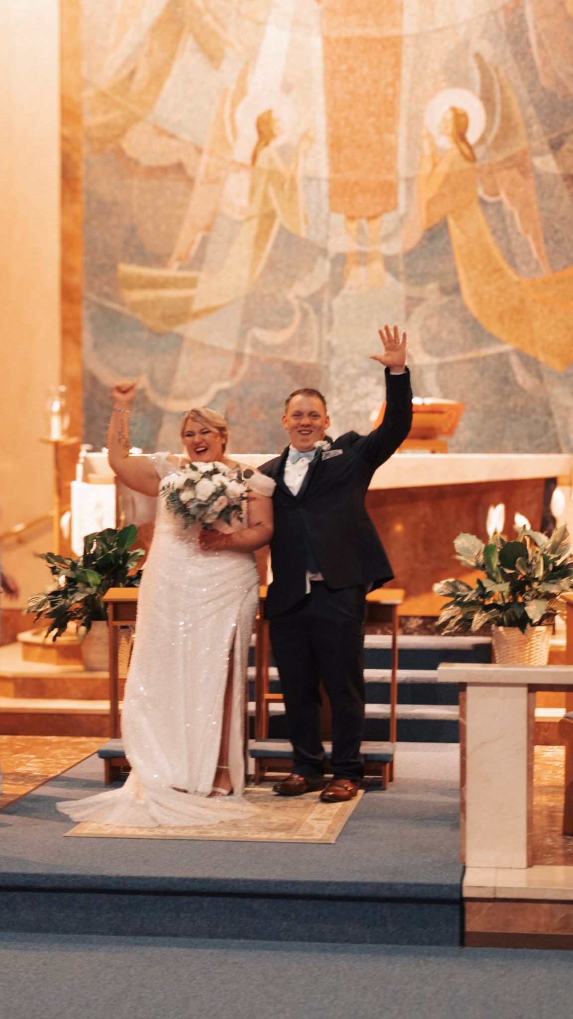 A happy couple celebrates joyfully at the altar during their wedding ceremony in a church with warm lighting.