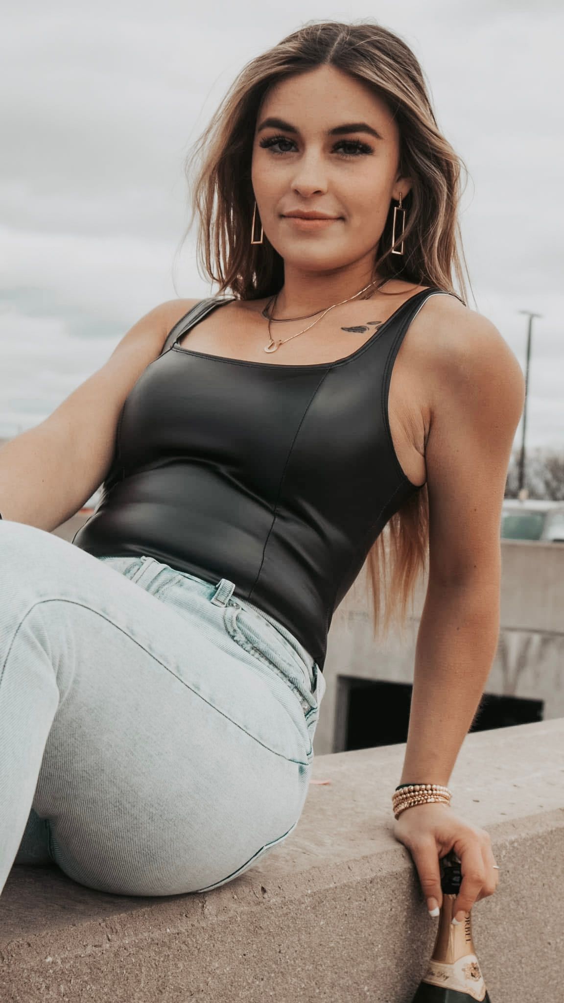 Fashion portrait series showing casual style with black tank top and light jeans against urban backdrop.