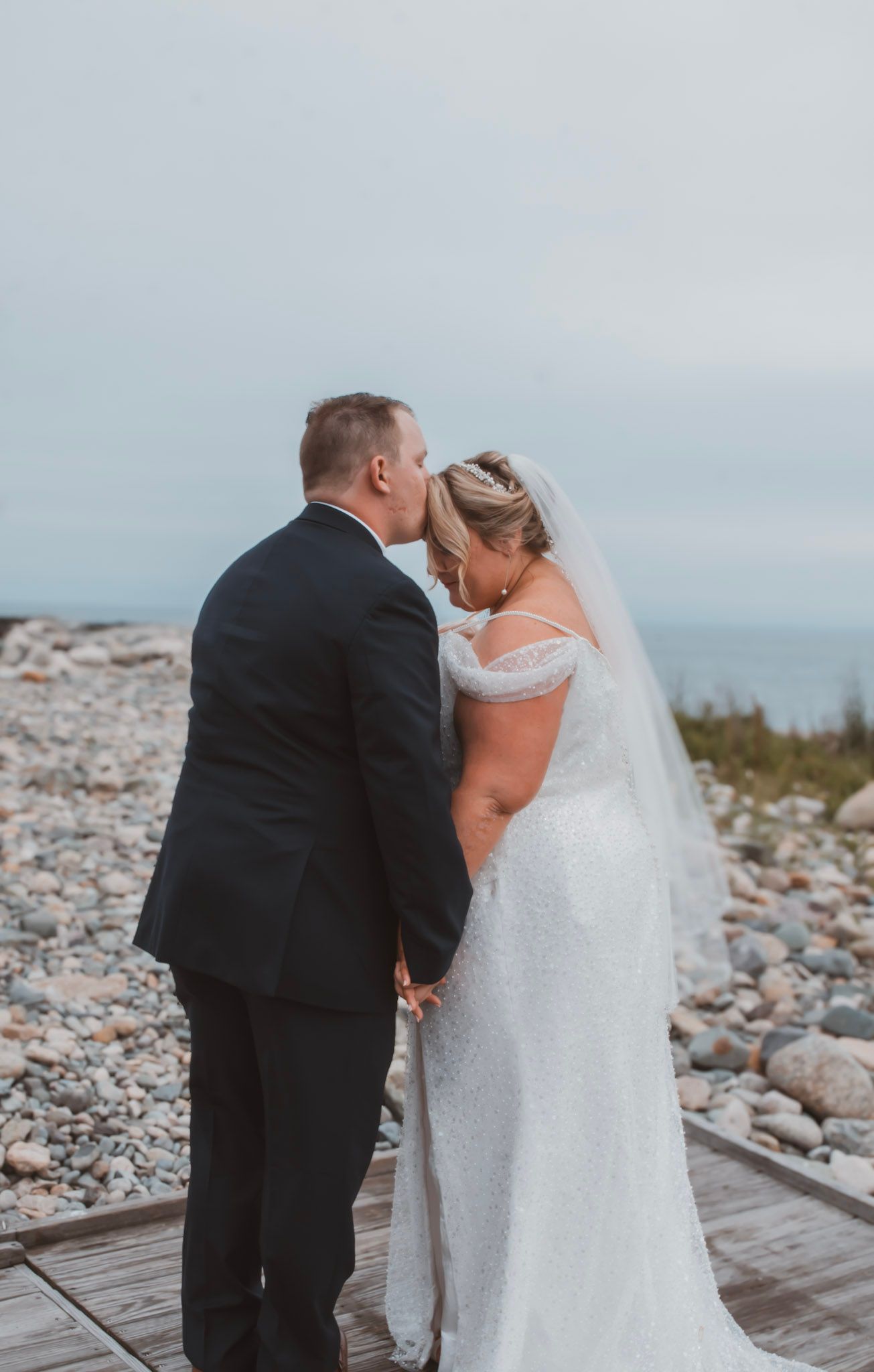 Color sequence of wedding photos capturing a couple sharing intimate moments on a wooden deck by a rocky shore.
