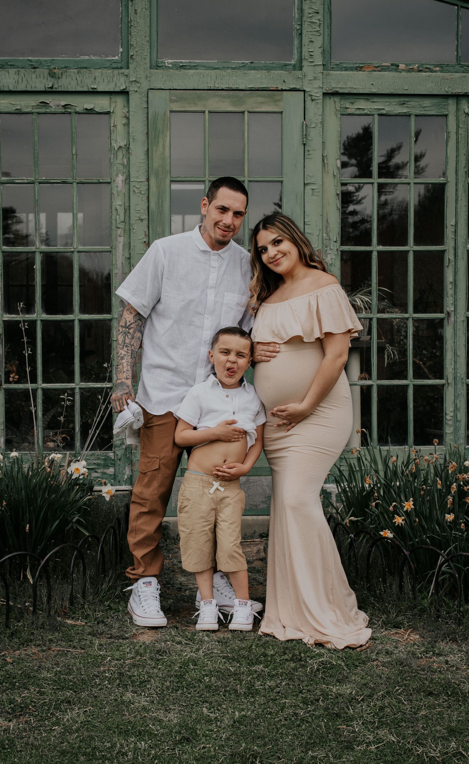 Maternity family portrait session in front of vintage green windows.