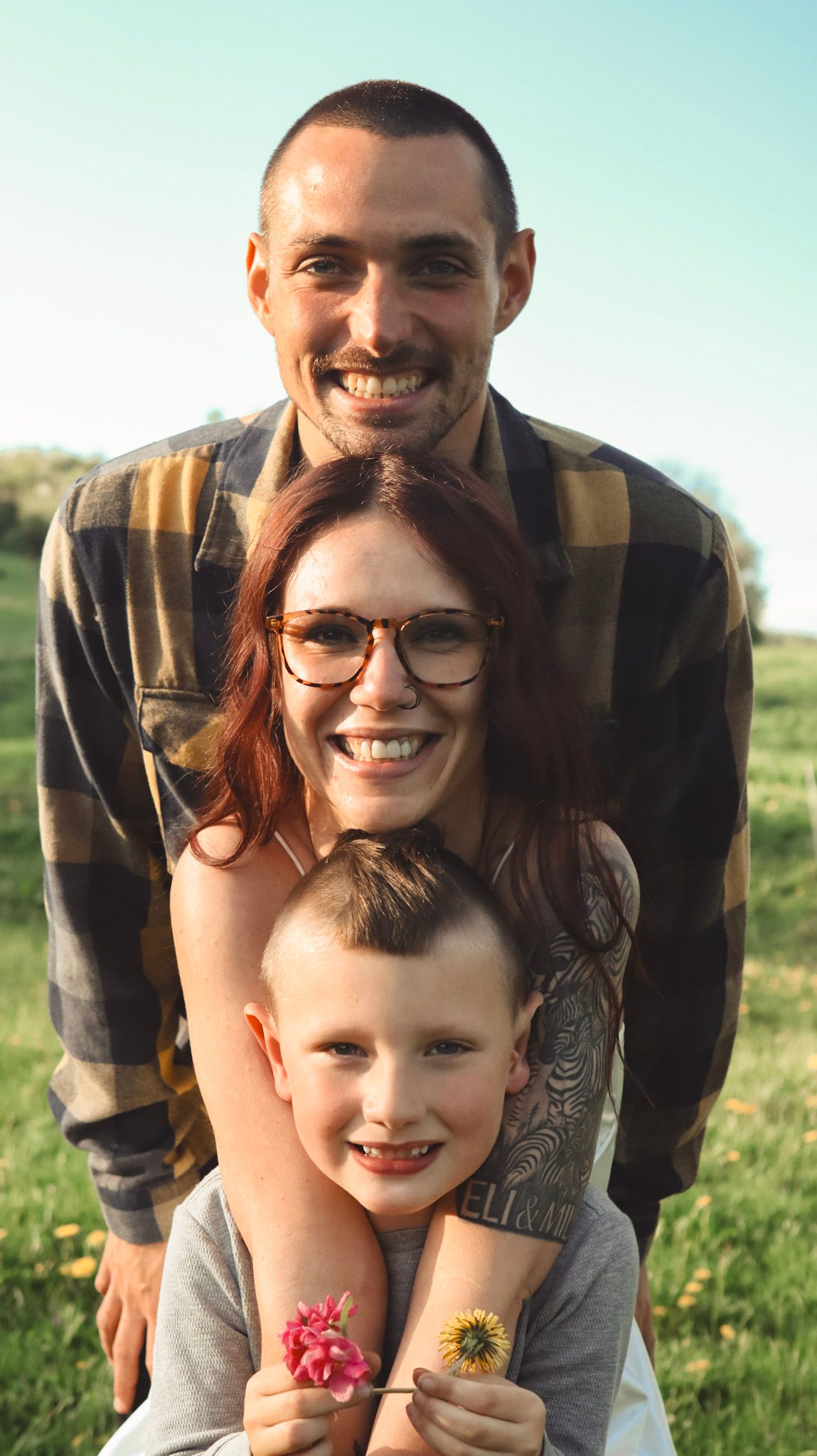 A series of candid outdoor family photos showing joyful expressions and warm embraces in a sunlit grassy field.