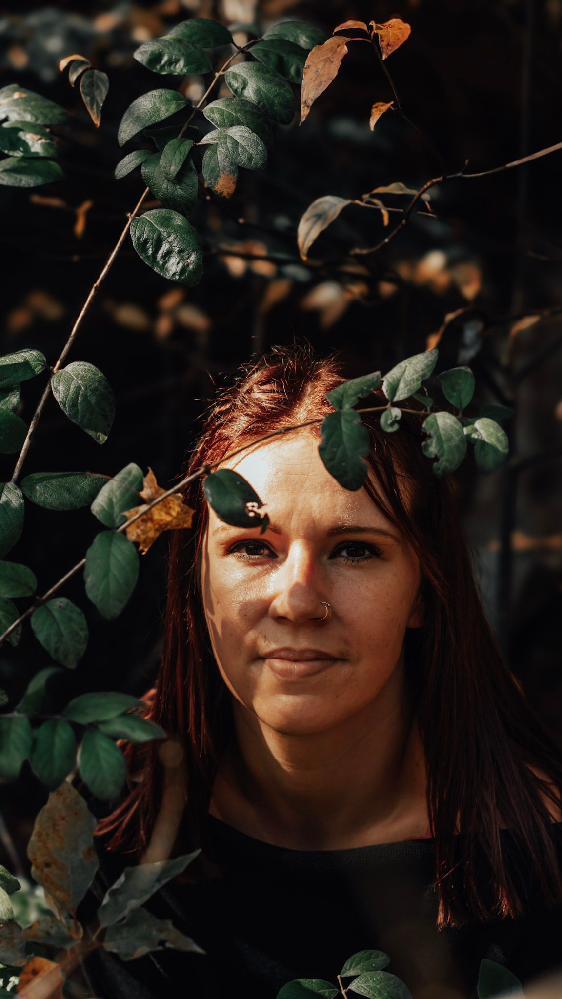Portrait series in a garden setting with green leaves and warm autumn lighting creating a mystical woodland atmosphere.