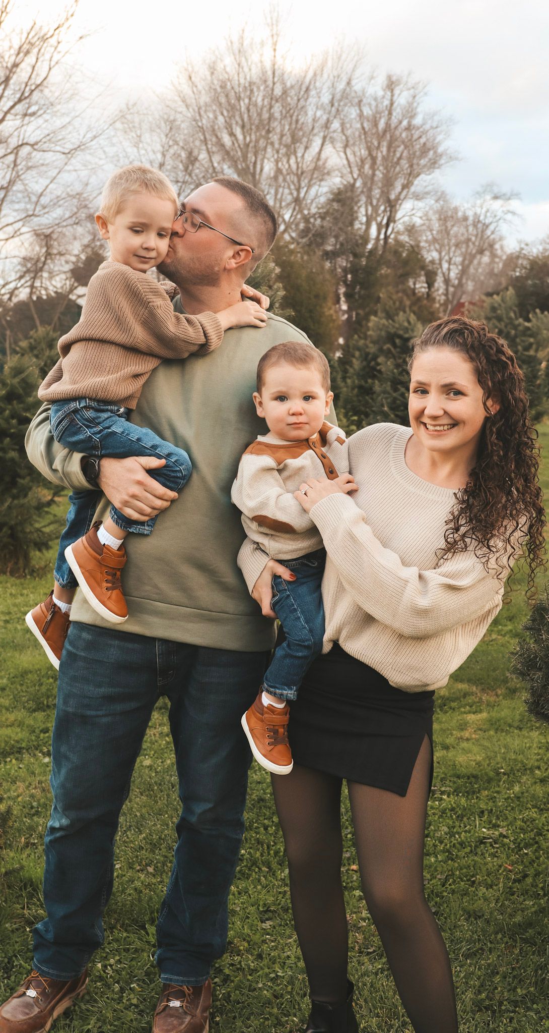 A family shares loving moments together in a series of candid outdoor photos on a grassy field during autumn.
