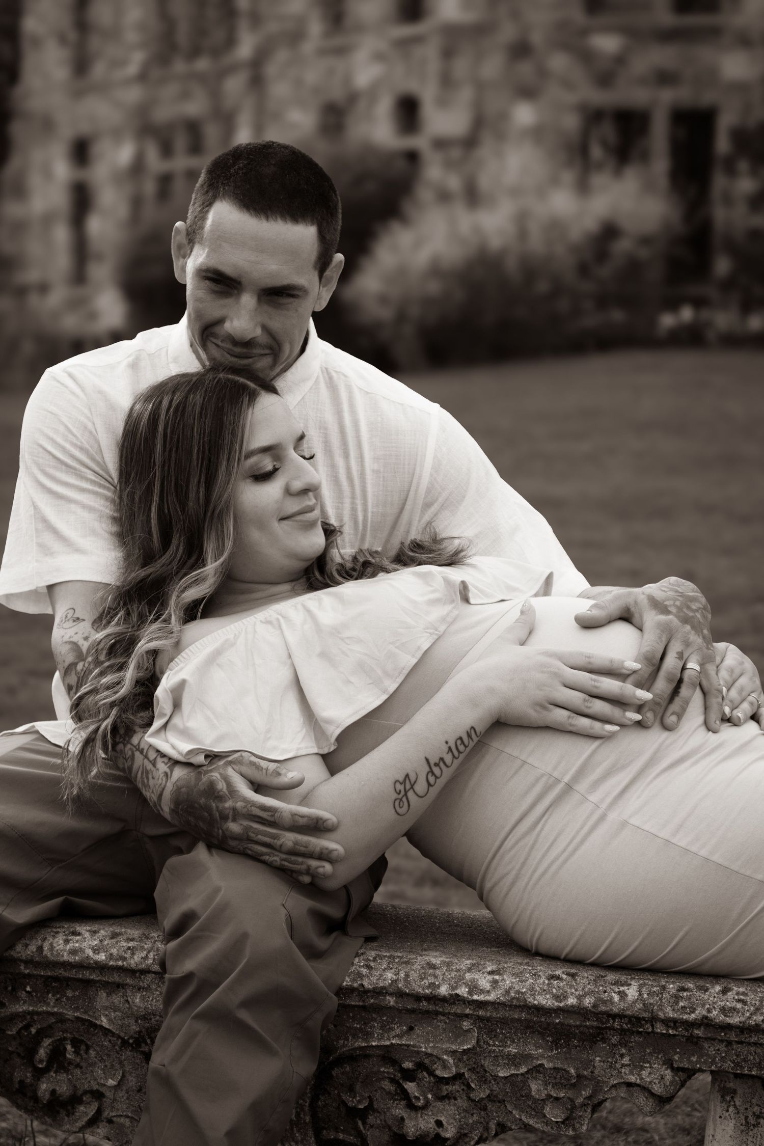 Black and white maternity photos capturing tender moments on stone architecture.