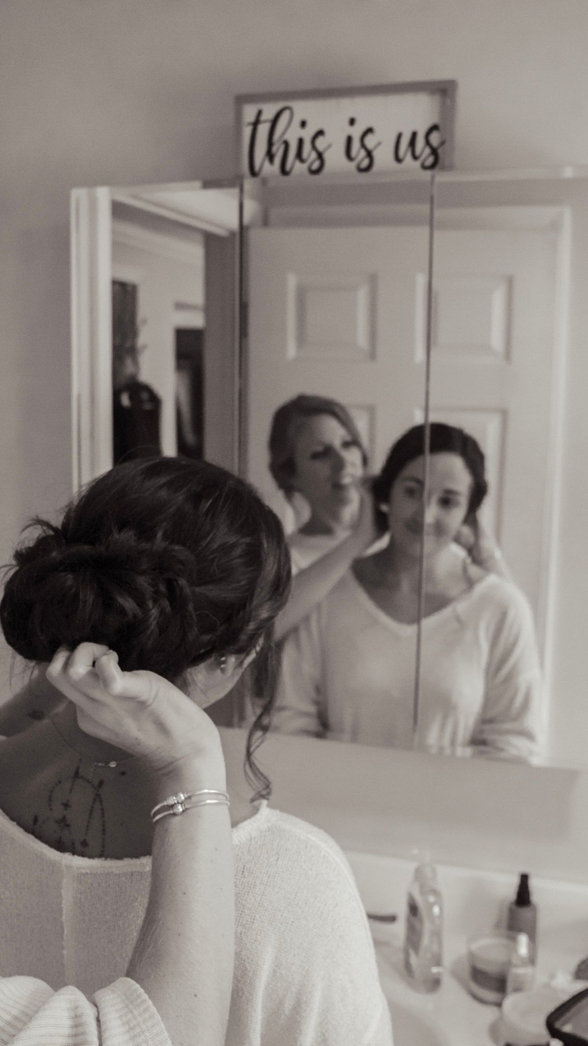 Getting ready scene with mirrors and 'this is us' text on wall.