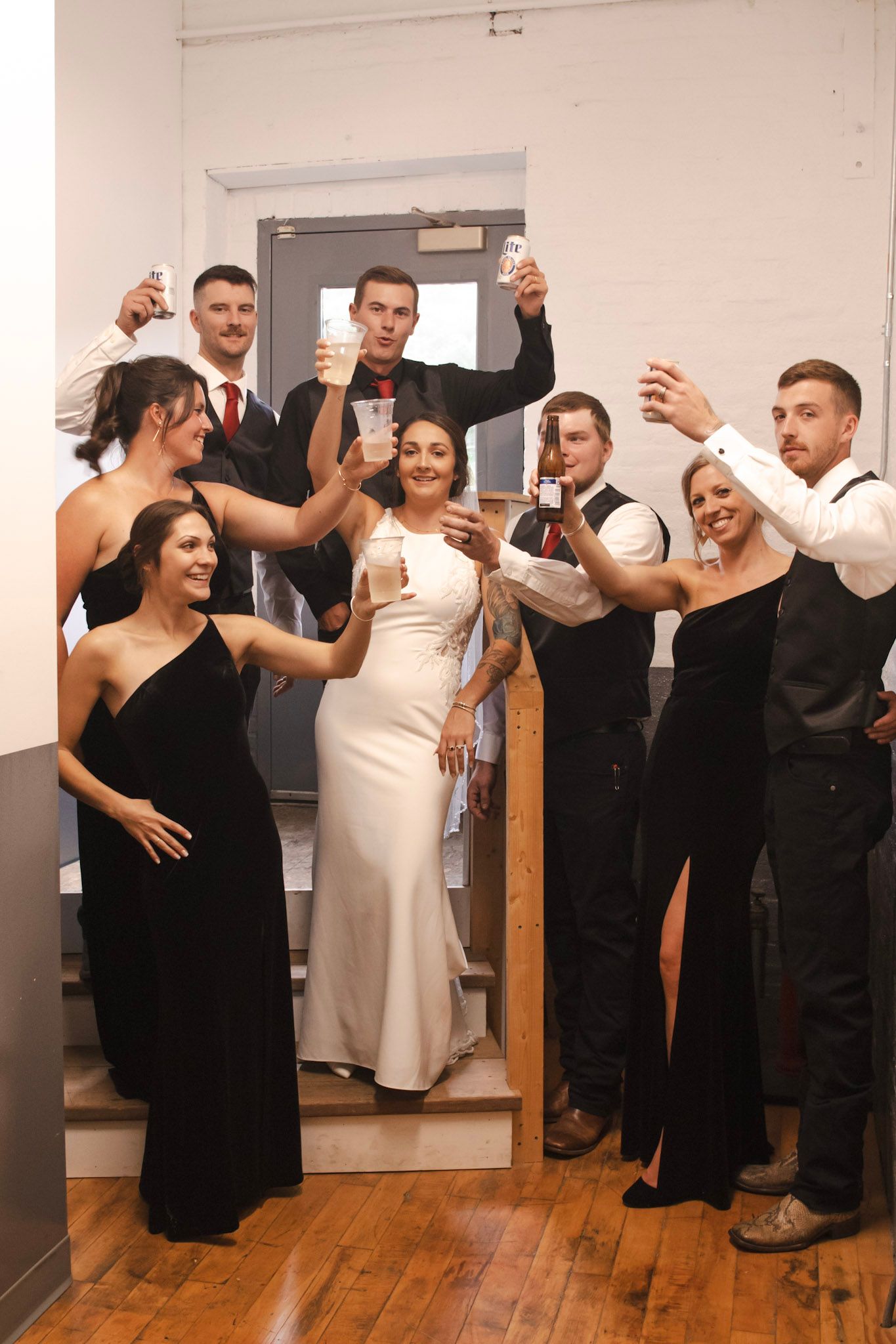 Wedding guests in black and white attire dancing and celebrating together in a room with wooden floors.