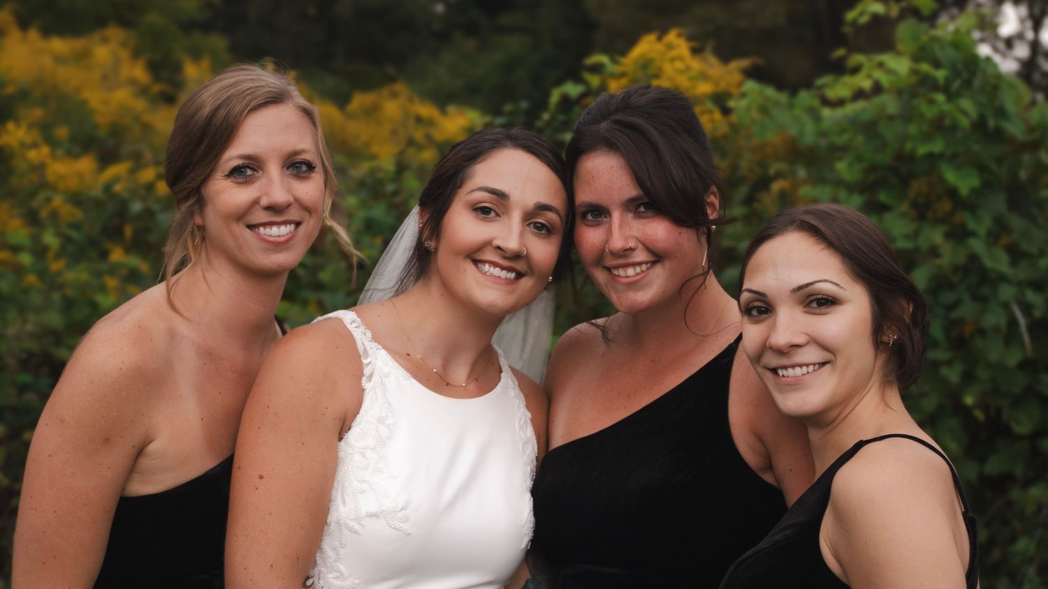 Group wearing formal attire posing together at outdoor event.