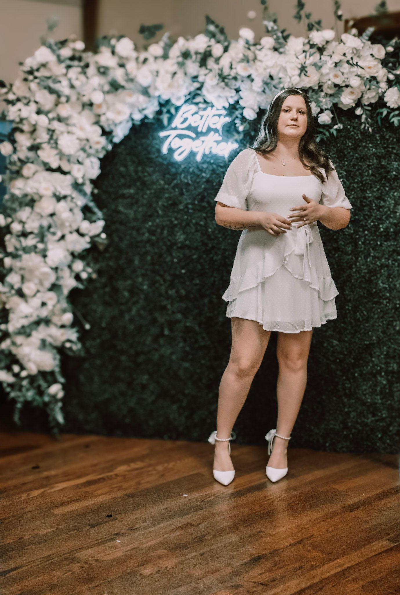 White floral backdrop with wooden flooring creates an elegant setting for a photoshoot.