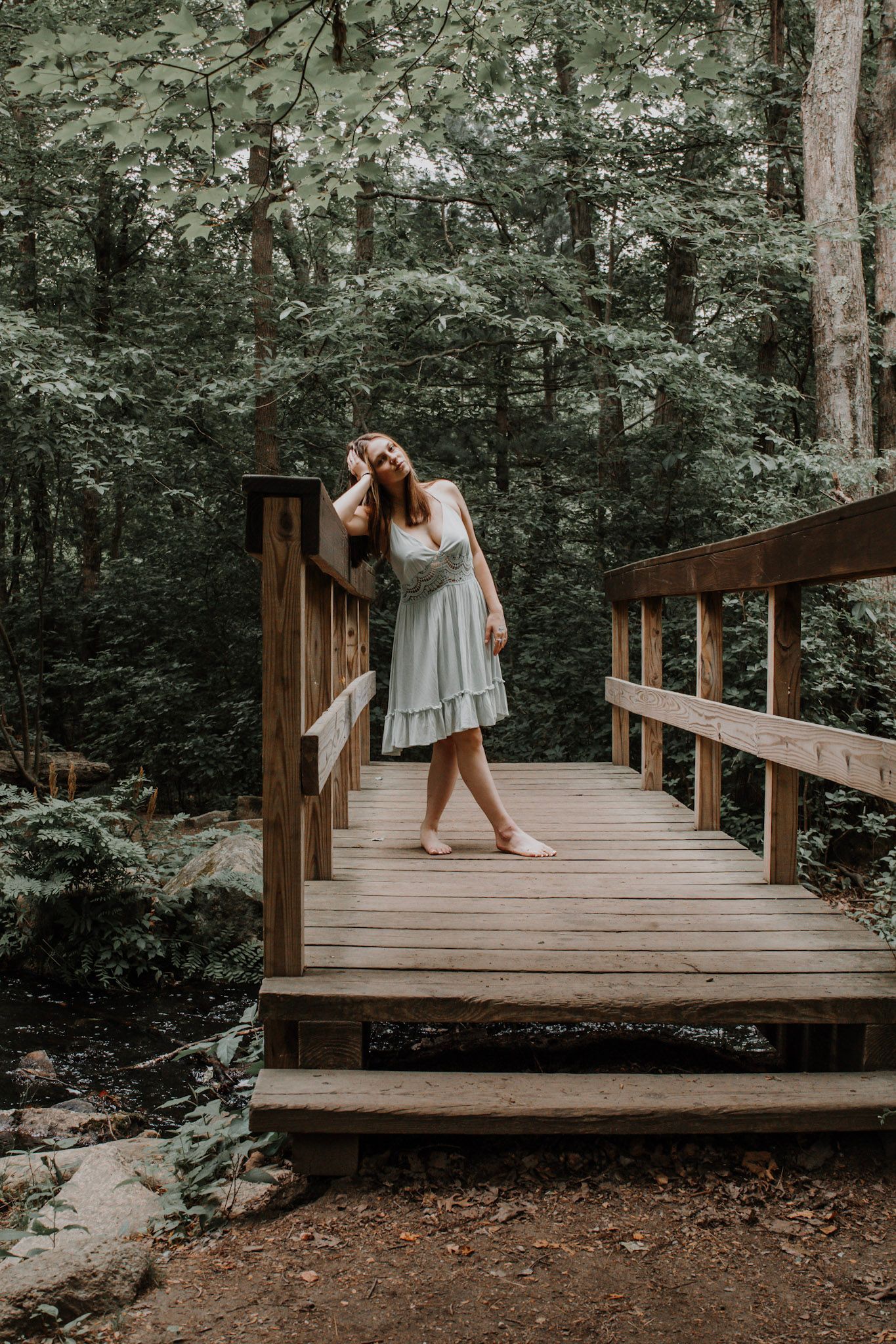 A wooden footbridge in a lush forest creates a serene natural setting for a photoshoot.
