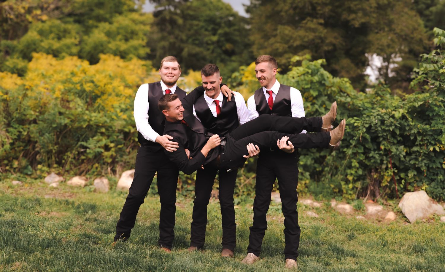 Wedding party poses playfully in a field with yellow wildflowers.