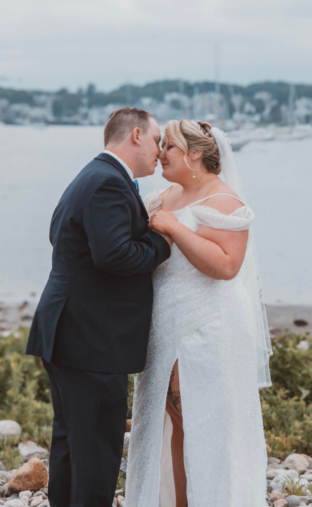 A romantic seaside wedding moment with a couple sharing an intimate kiss against a coastal backdrop.