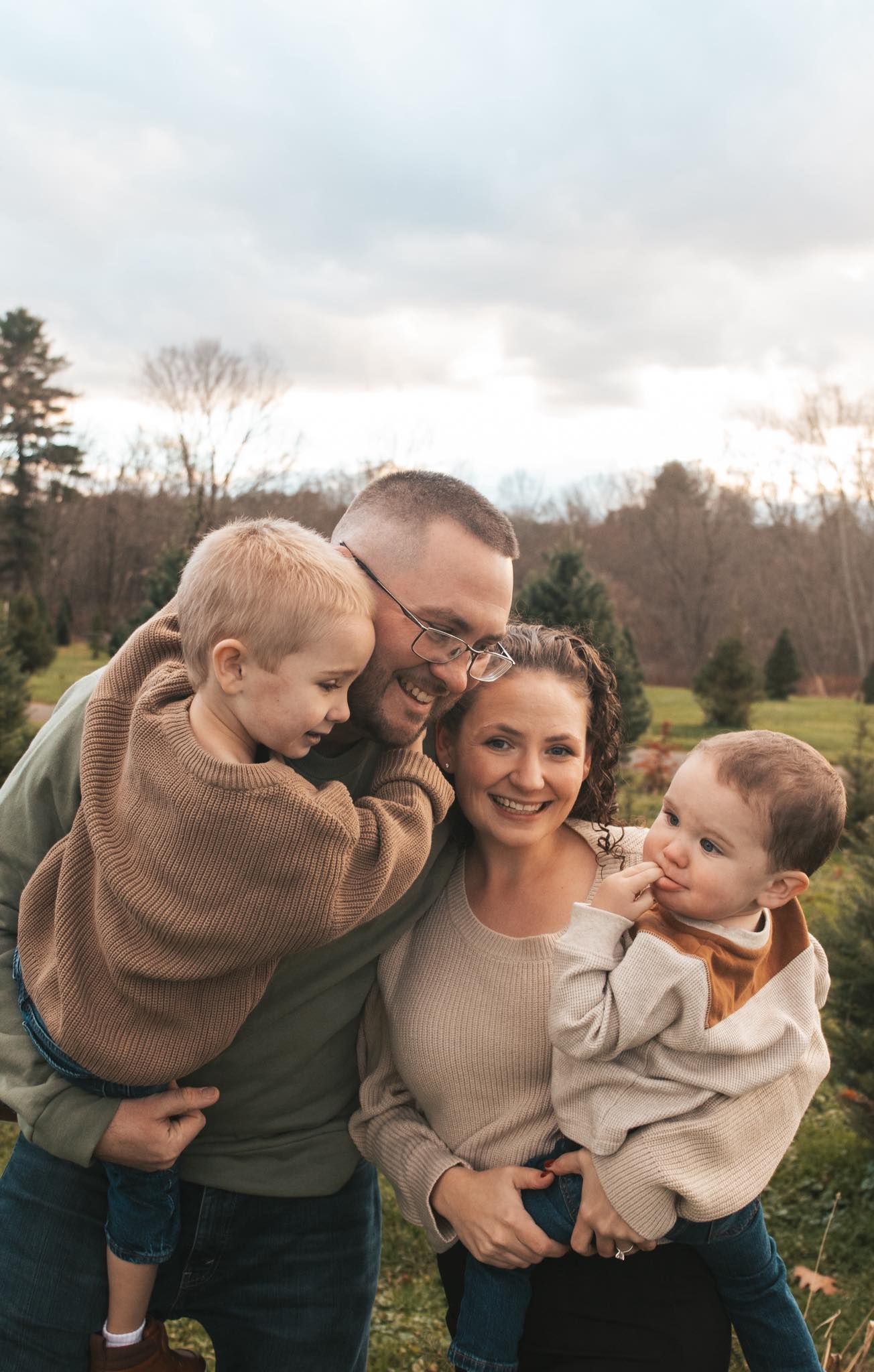 Family sharing tender moment outdoors in matching neutral sweaters.