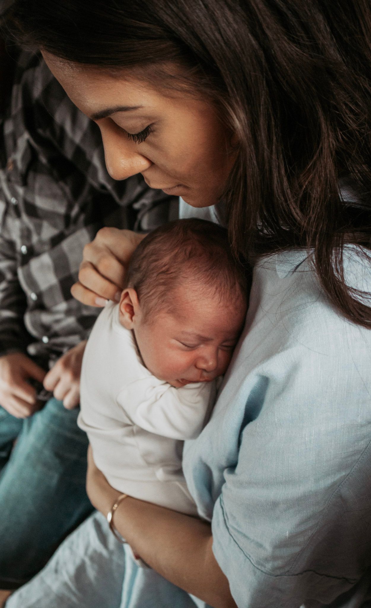 A tender moment between mother and newborn as they share intimate cuddles in soft natural light.