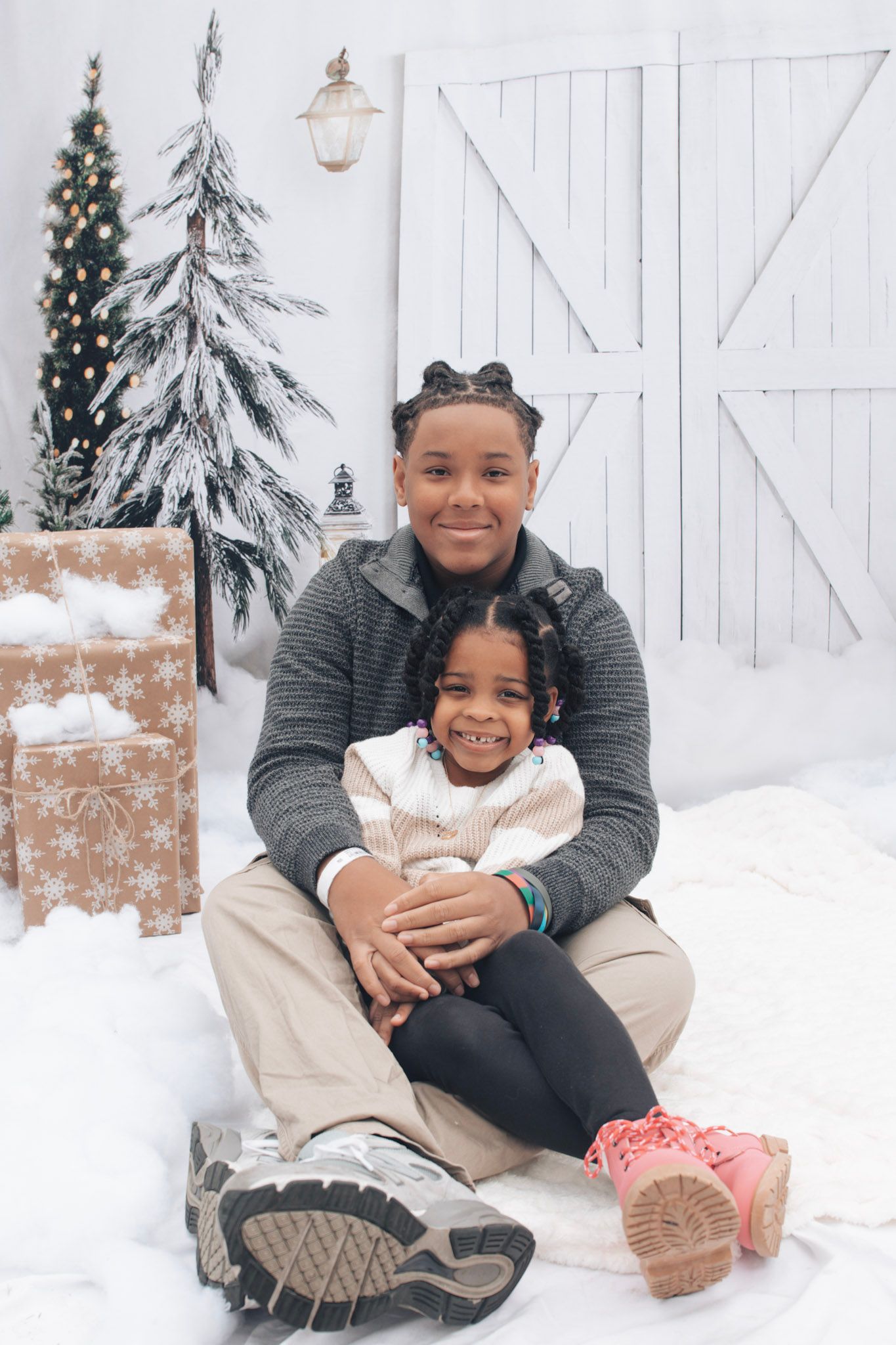 Parent and child sitting together in casual winter outfits against snowy backdrop with decorative lantern.